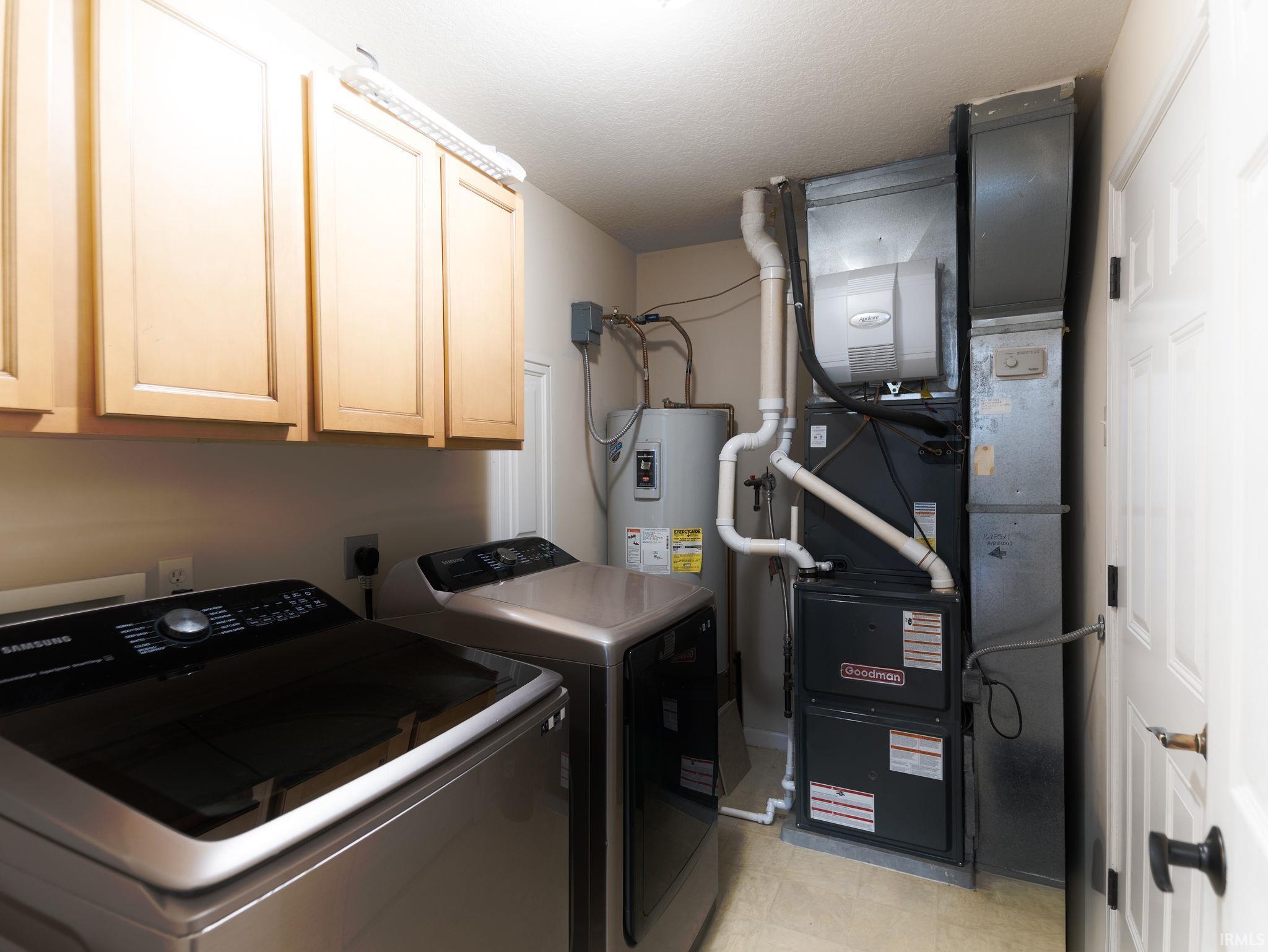Utility area featuring overhead cabinetry, a water heater, and a furnace system