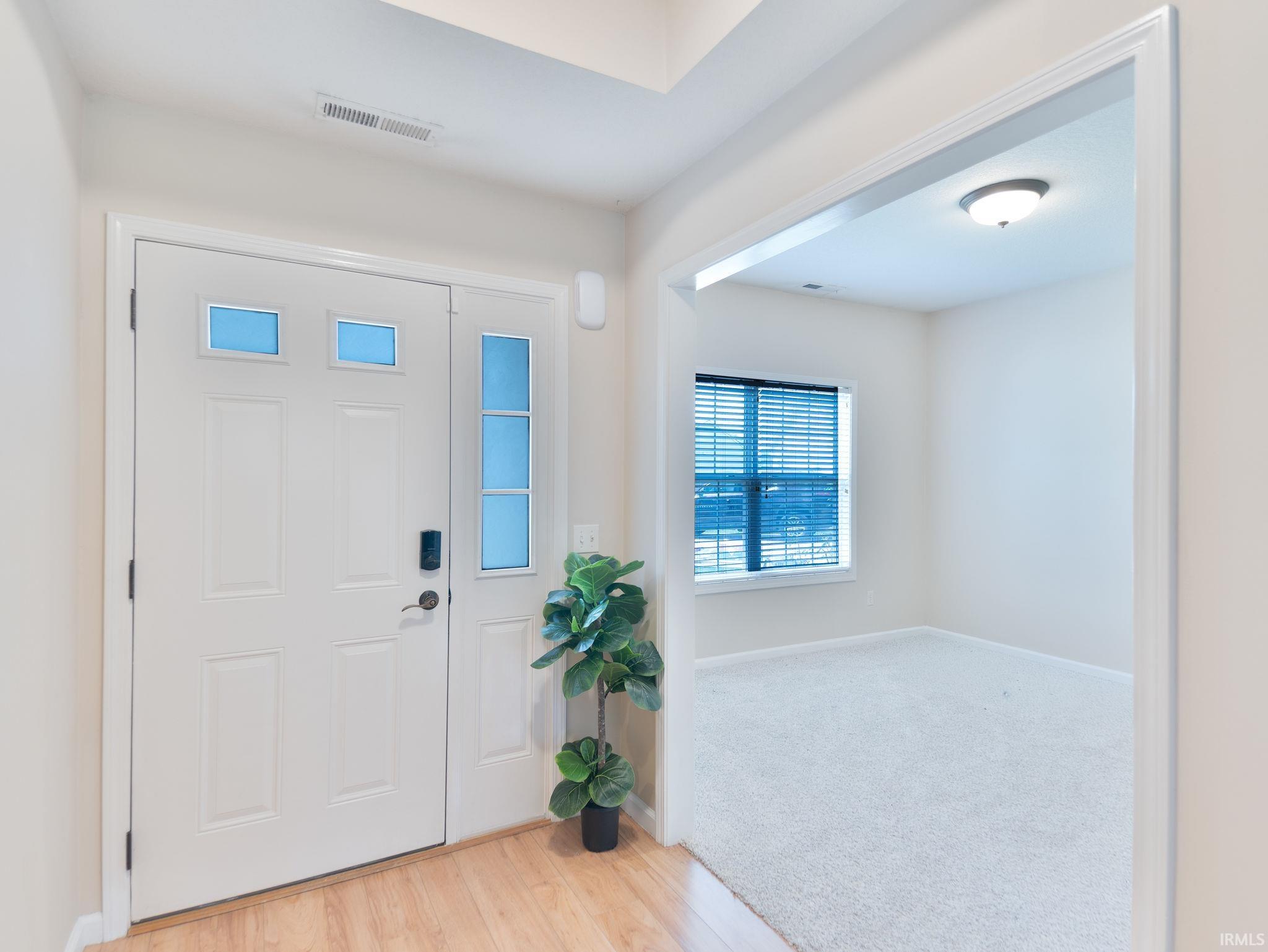 Entryway featuring a paneled door with glass inserts, sidelight, and wood-finish flooring