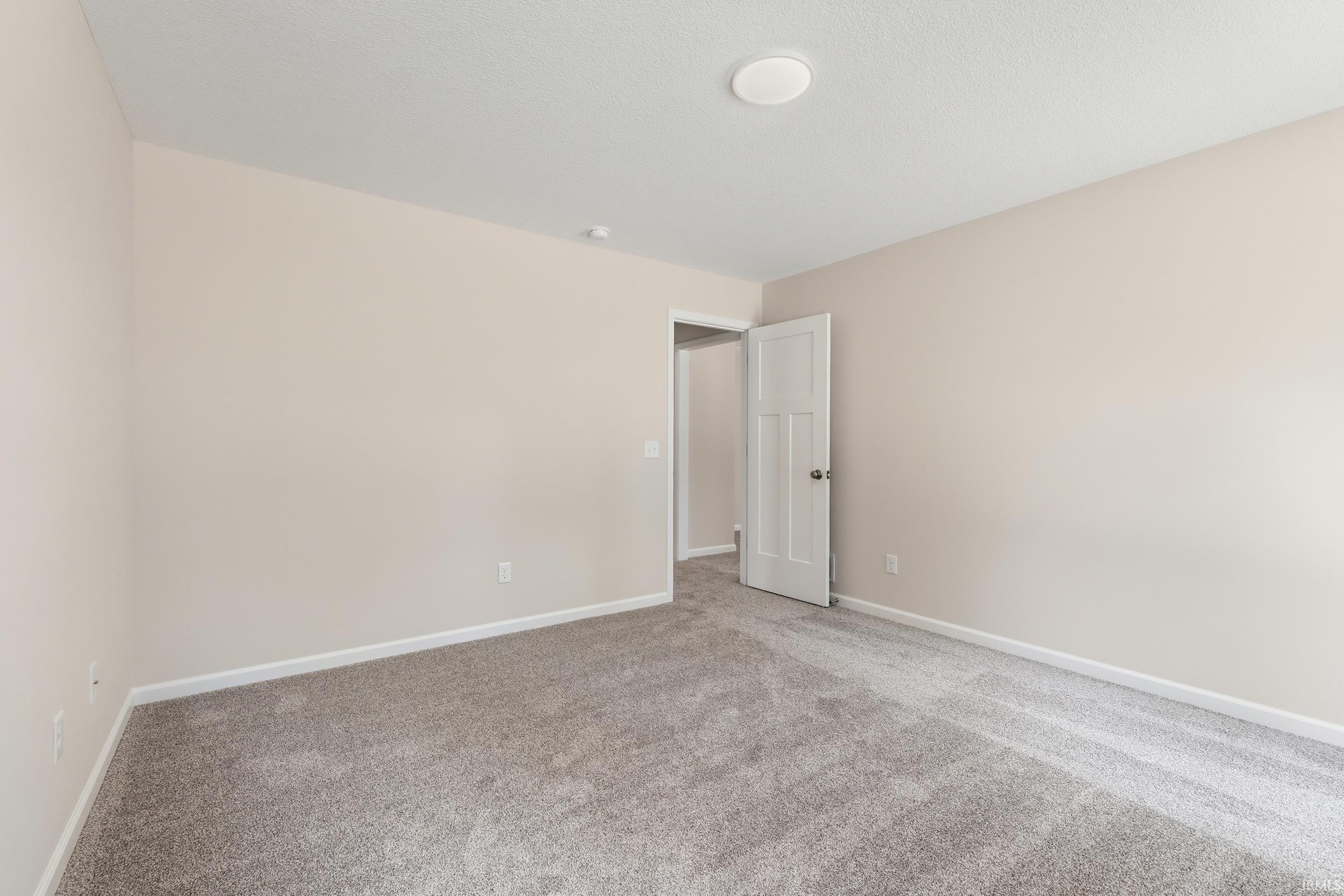 Spacious room featuring neutral carpeting, light-toned wall paint, and white trim