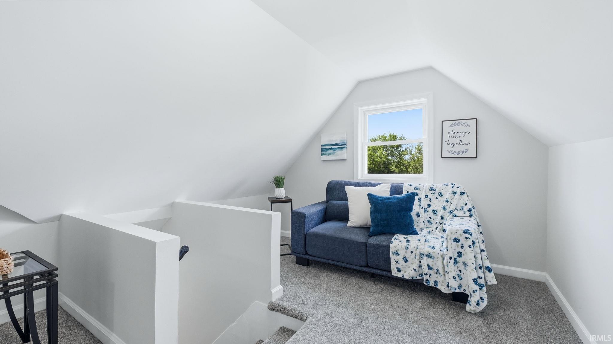 Upper level space featuring vaulted ceilings, a single window providing natural light, and gray carpeting