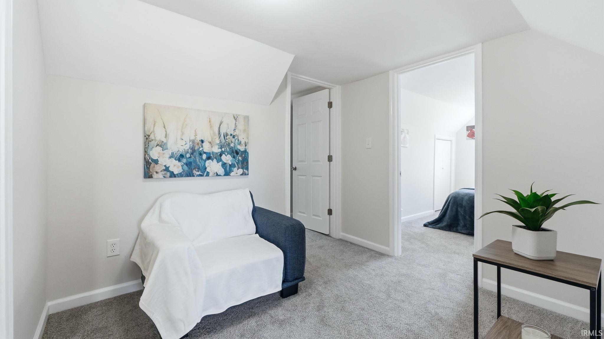 Carpeted room with sloped ceilings and a neutral wall color