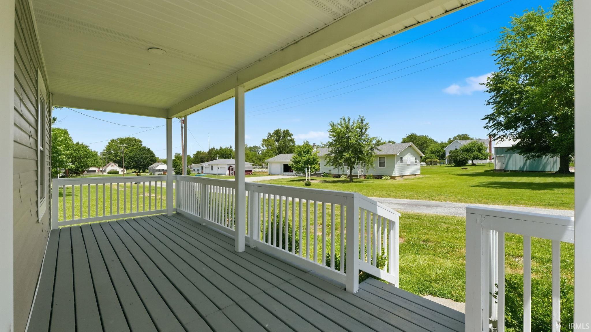 Covered front porch with grey wood-finish decking and white baluster railing