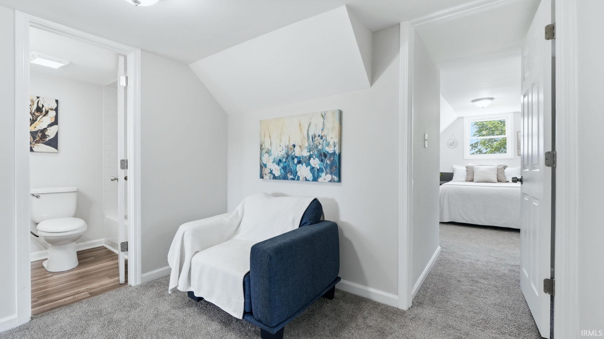 Carpeted hallway with a sloped ceiling and recessed lighting