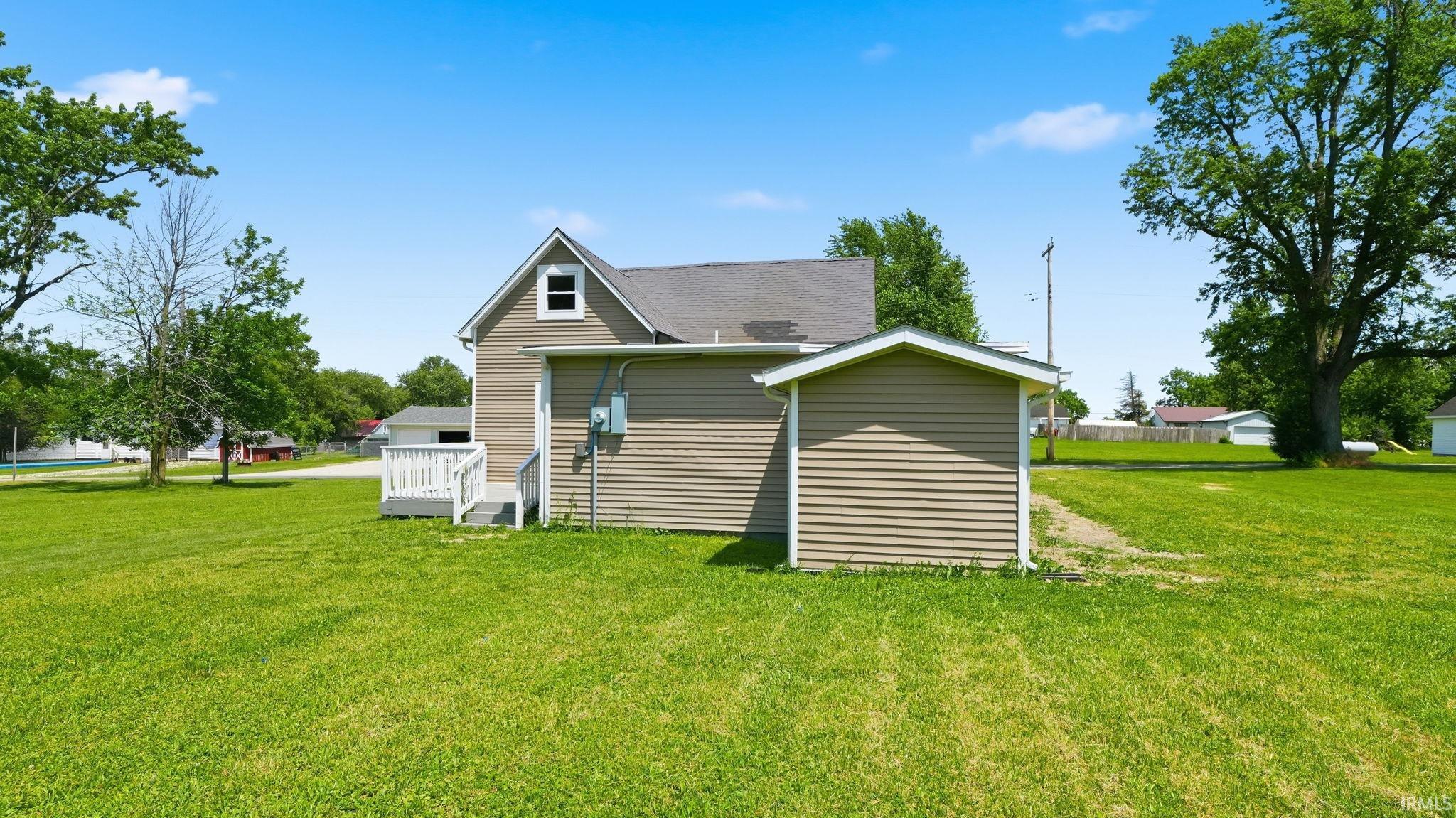 Spacious rear yard with a detached storage shed, exterior vinyl siding, and a rear deck with white railing