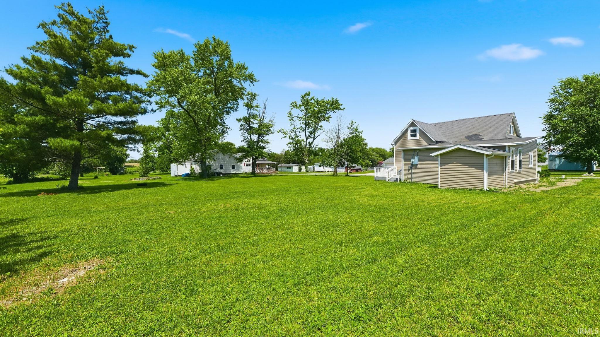 Expansive green lawn surrounds a two-story residence featuring light gray siding, white trim, and a dark gray roof