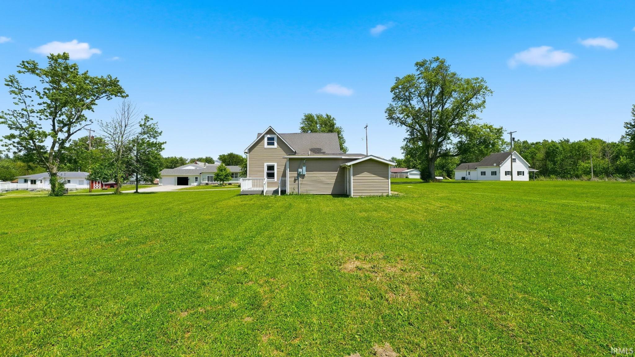 Expansive green lawn surrounding a two-story residence with a detached outbuilding
