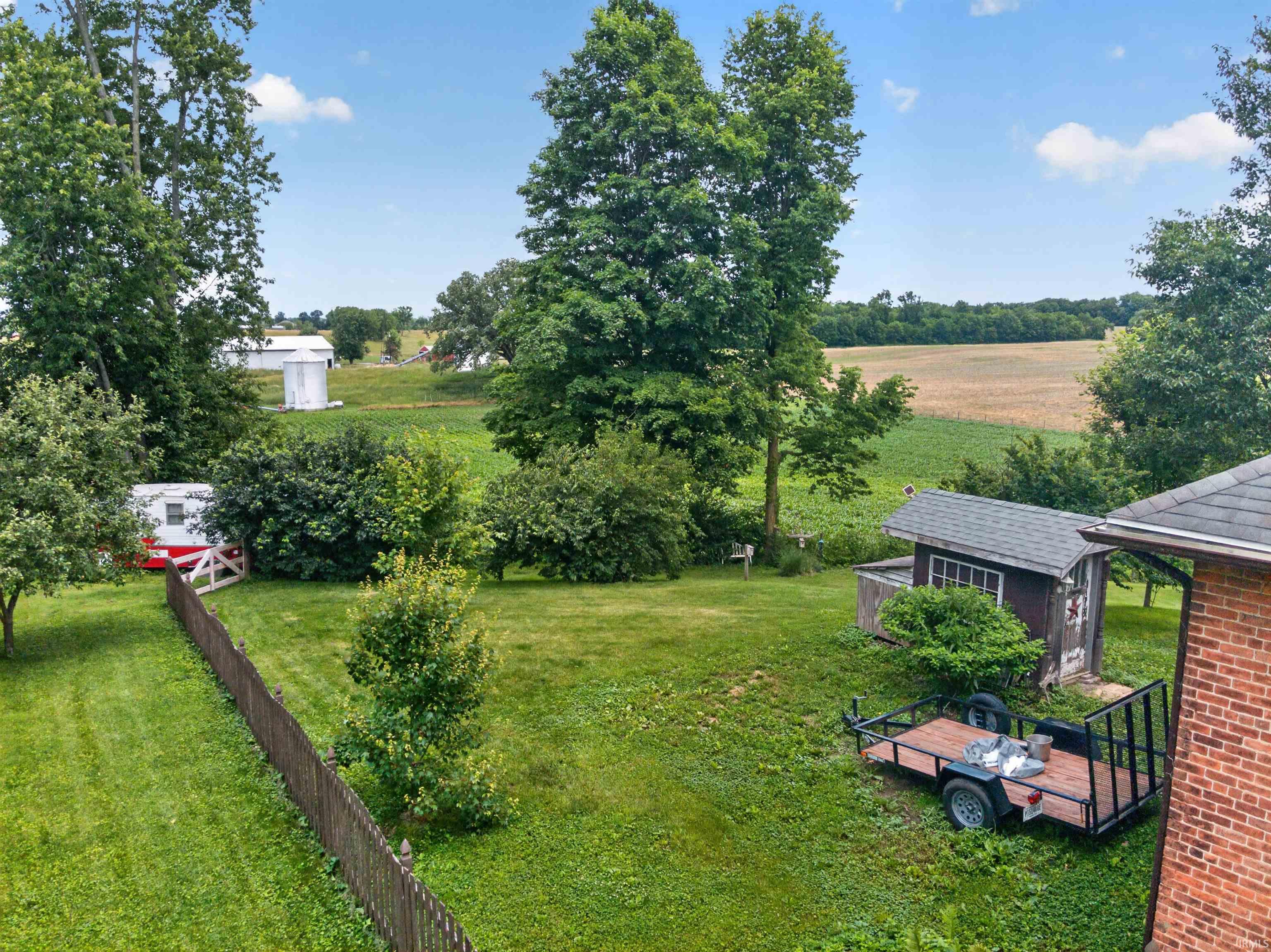 Expansive backyard featuring a lush green lawn, mature trees, and a wooden fence