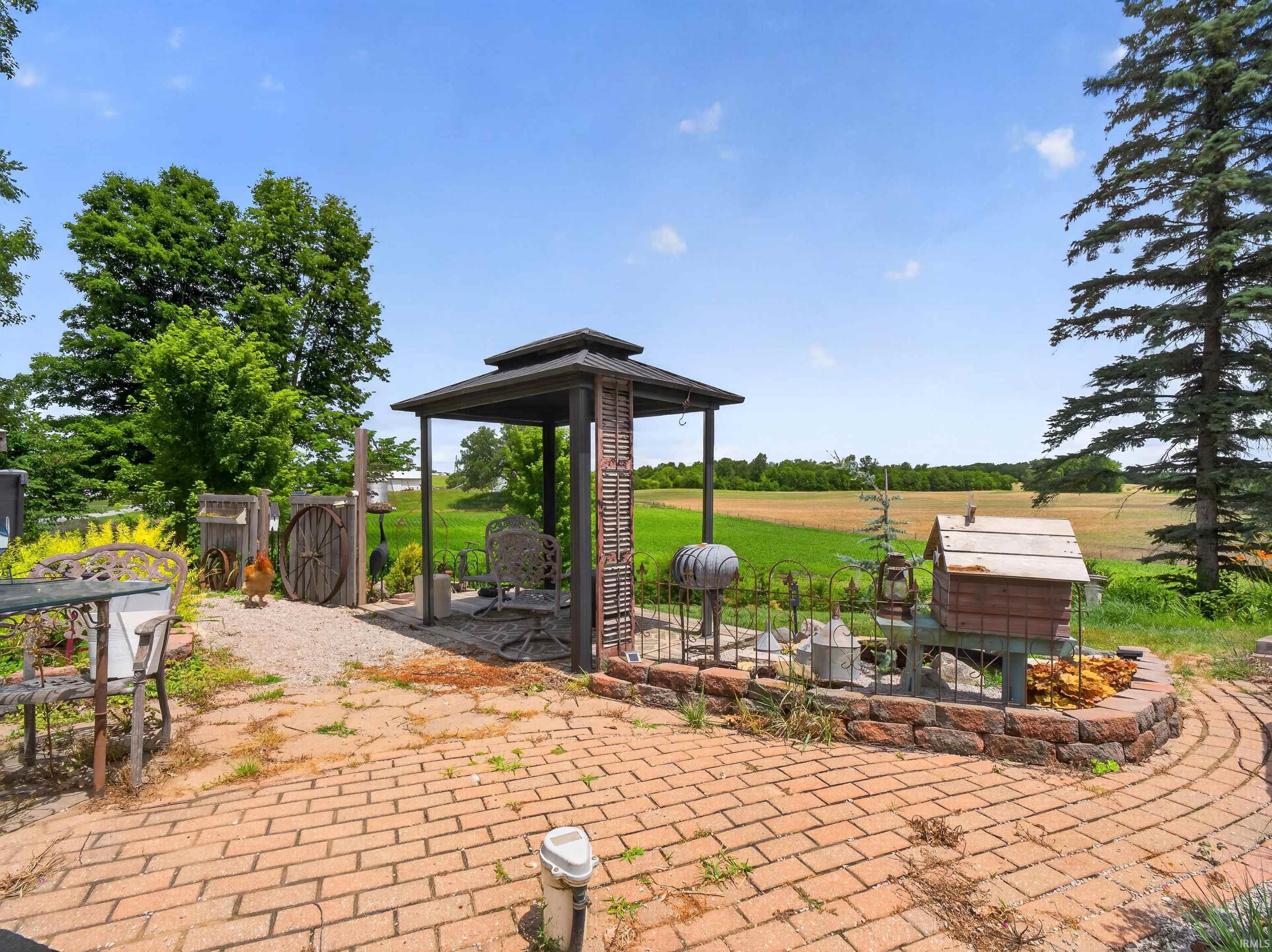 Brick paver patio with a low stone wall and a freestanding gazebo