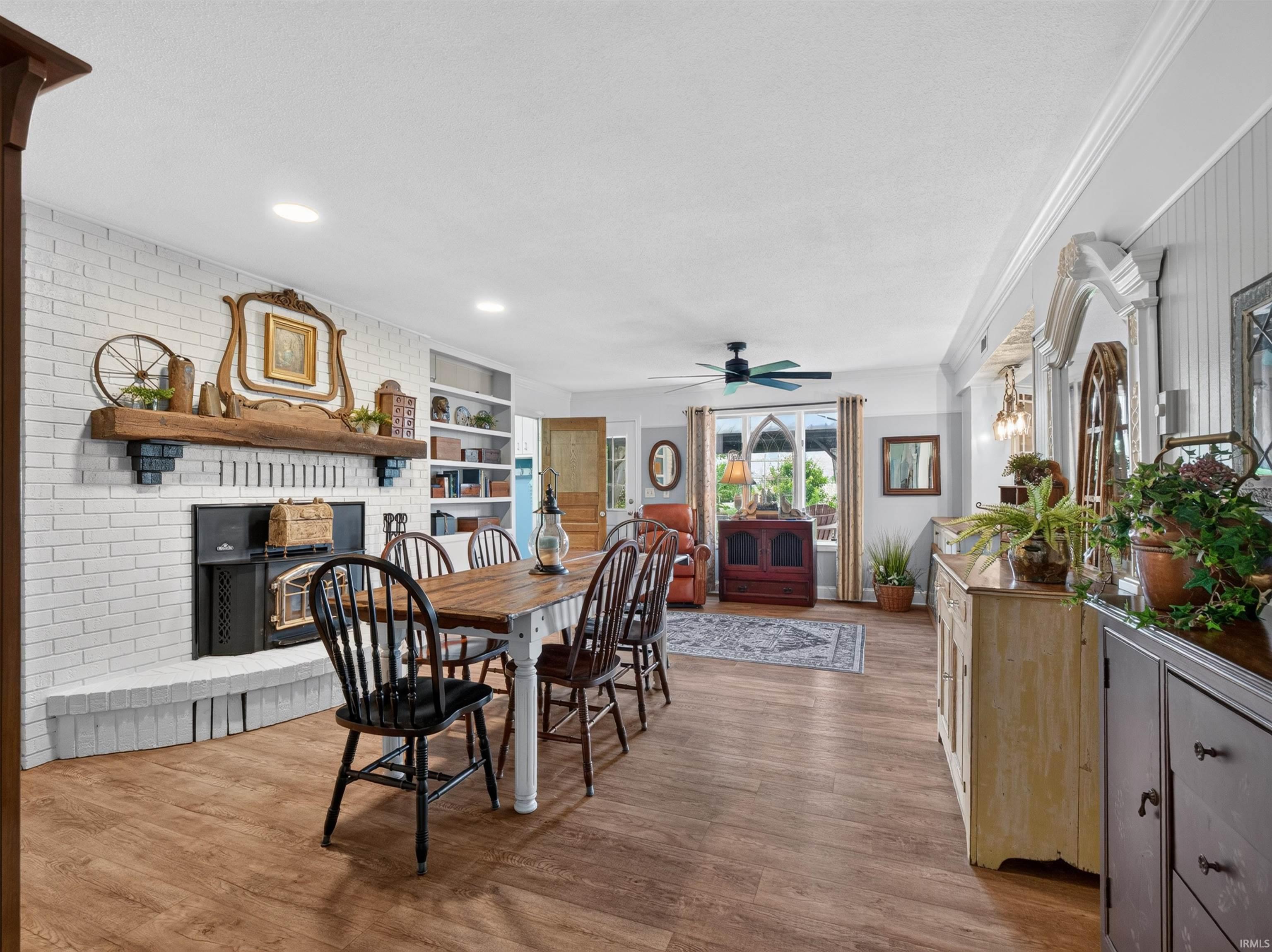 Spacious interior featuring wood-finish flooring, a white brick fireplace with a wood mantel, recessed lighting, and built-in shelving