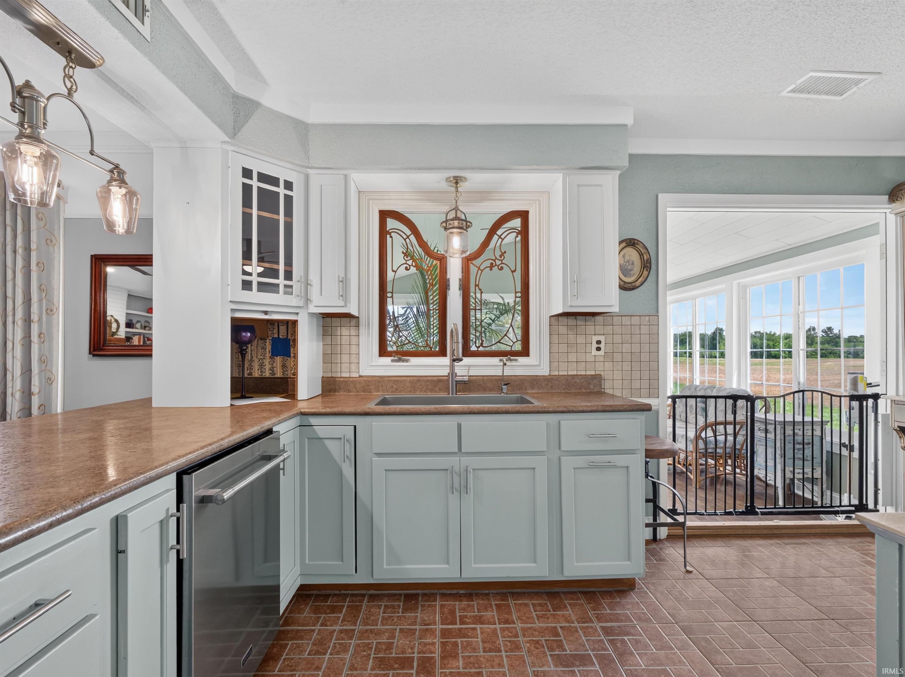 Kitchen featuring light blue lower cabinetry, white upper cabinetry, and a stainless steel dishwasher