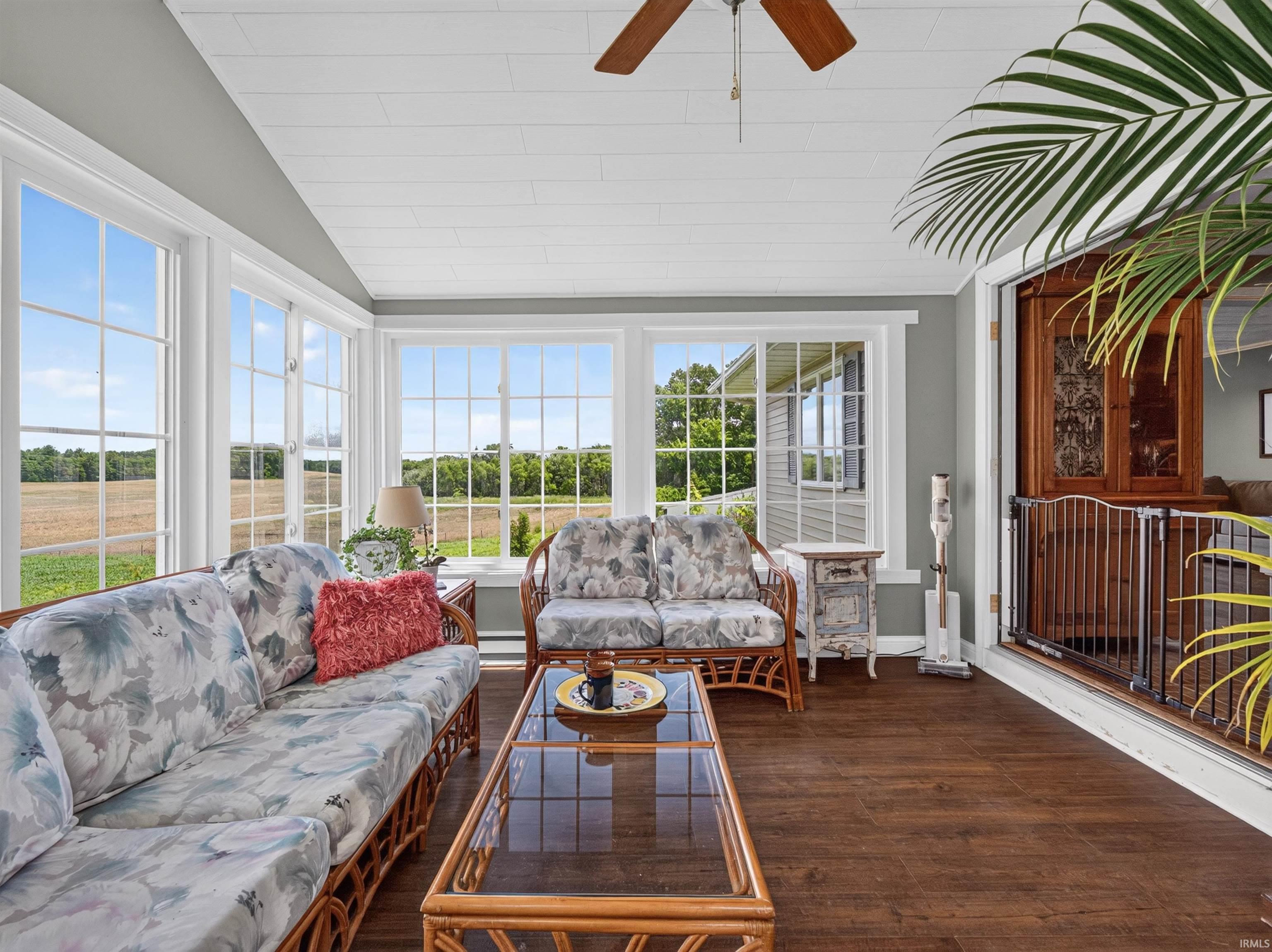 Sunroom with expansive windows, wood-finish flooring, a white plank ceiling, and a ceiling fan