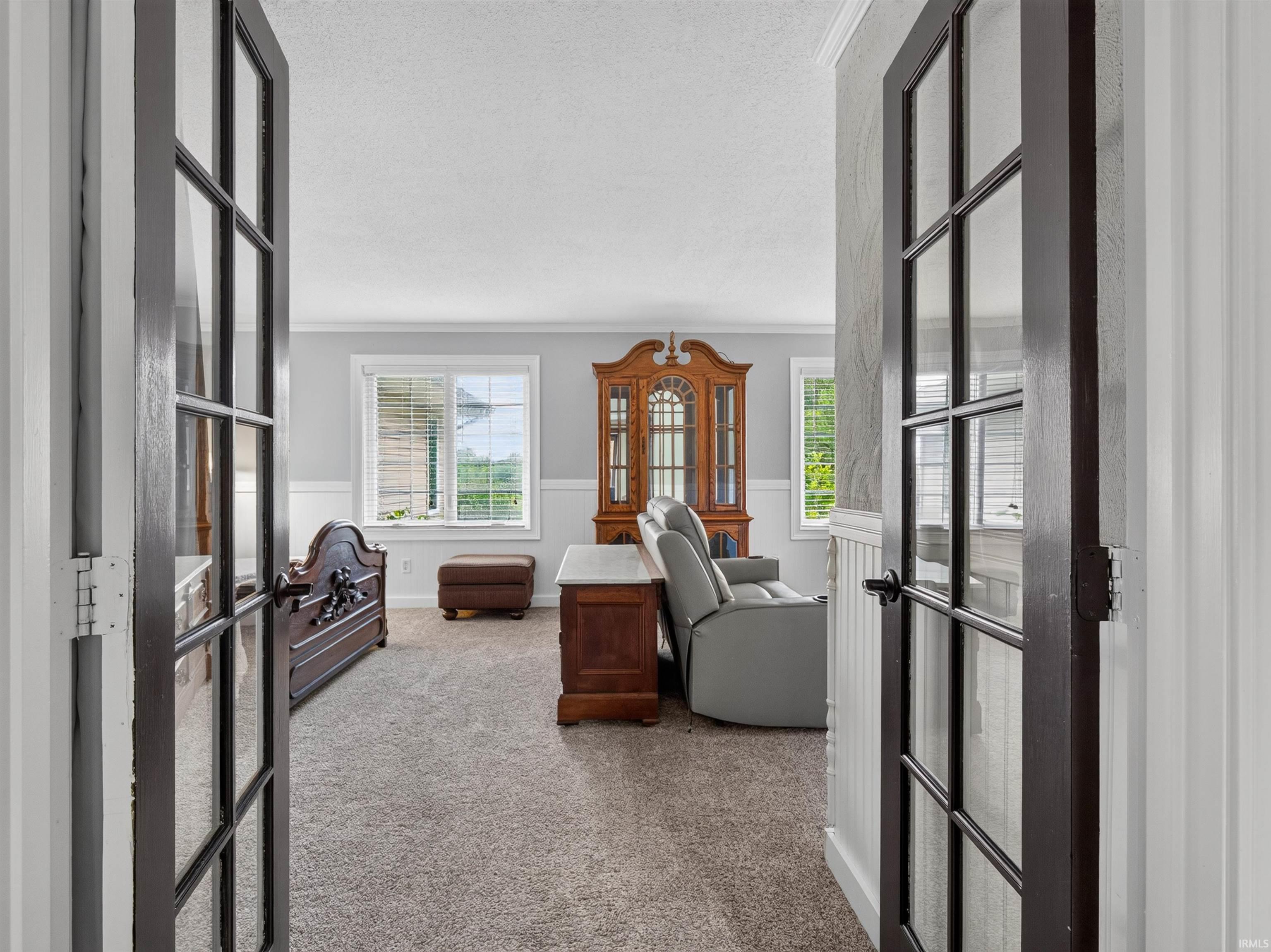 Double French doors with dark framing and clear glass panes open into a carpeted interior space