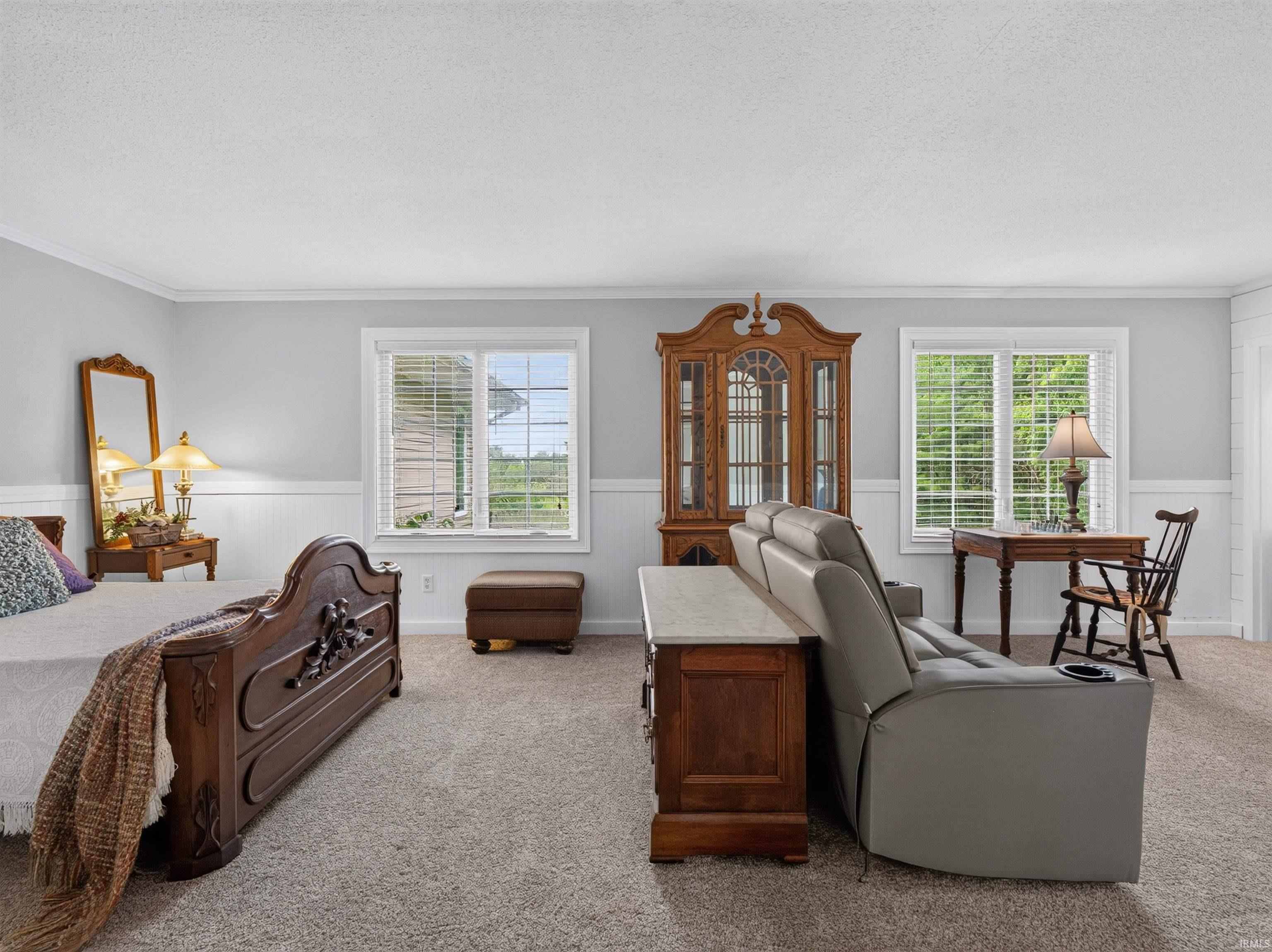 Spacious room featuring light gray walls, white wainscoting, and crown molding