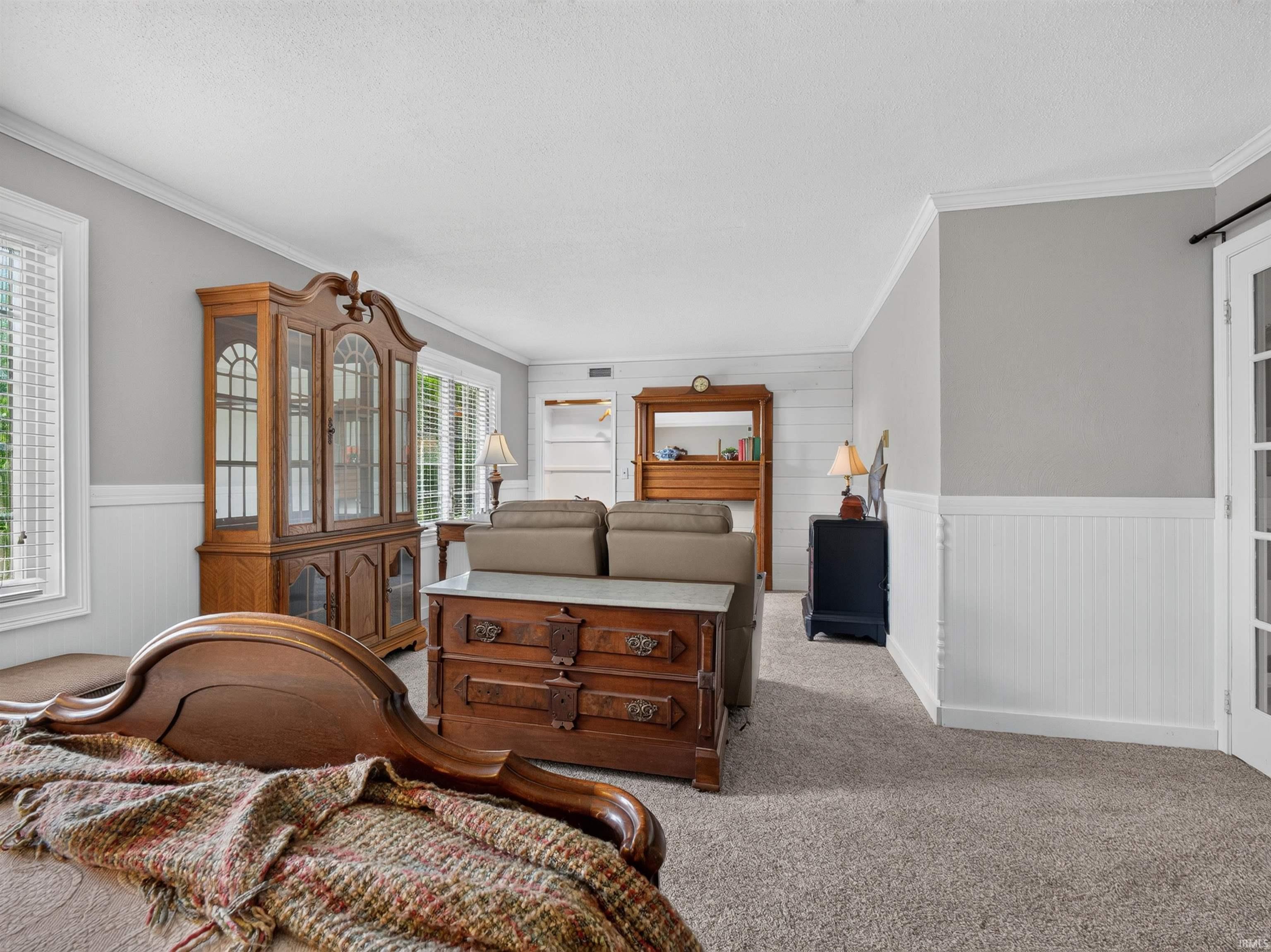 Expansive room featuring light gray walls, white beadboard wainscoting, and crown molding