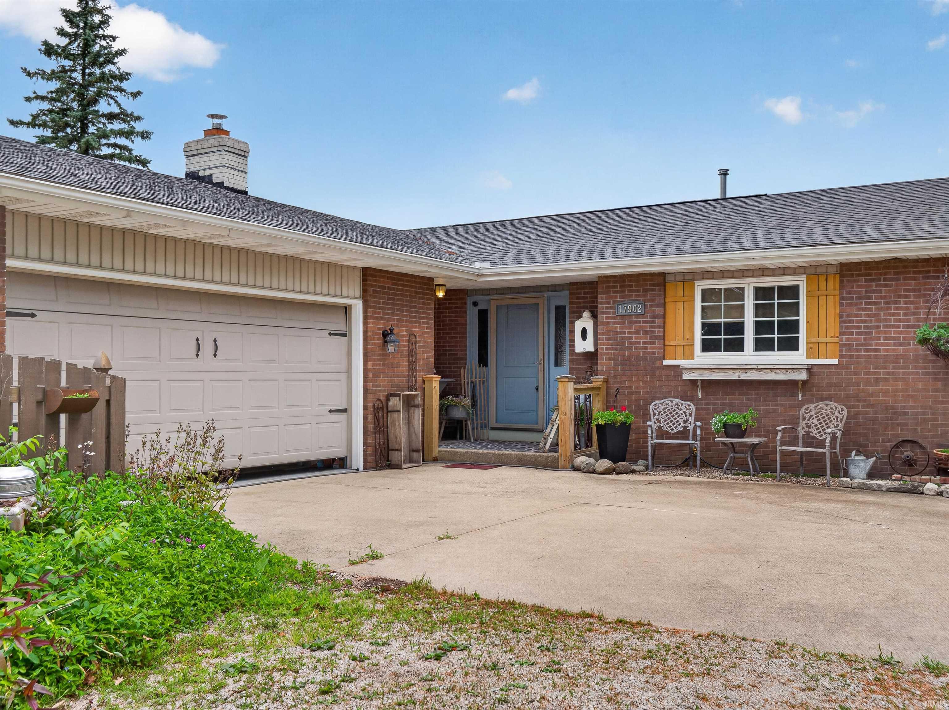 Brick exterior featuring a light blue front door, front window with wooden shutters, and an attached two-car garage