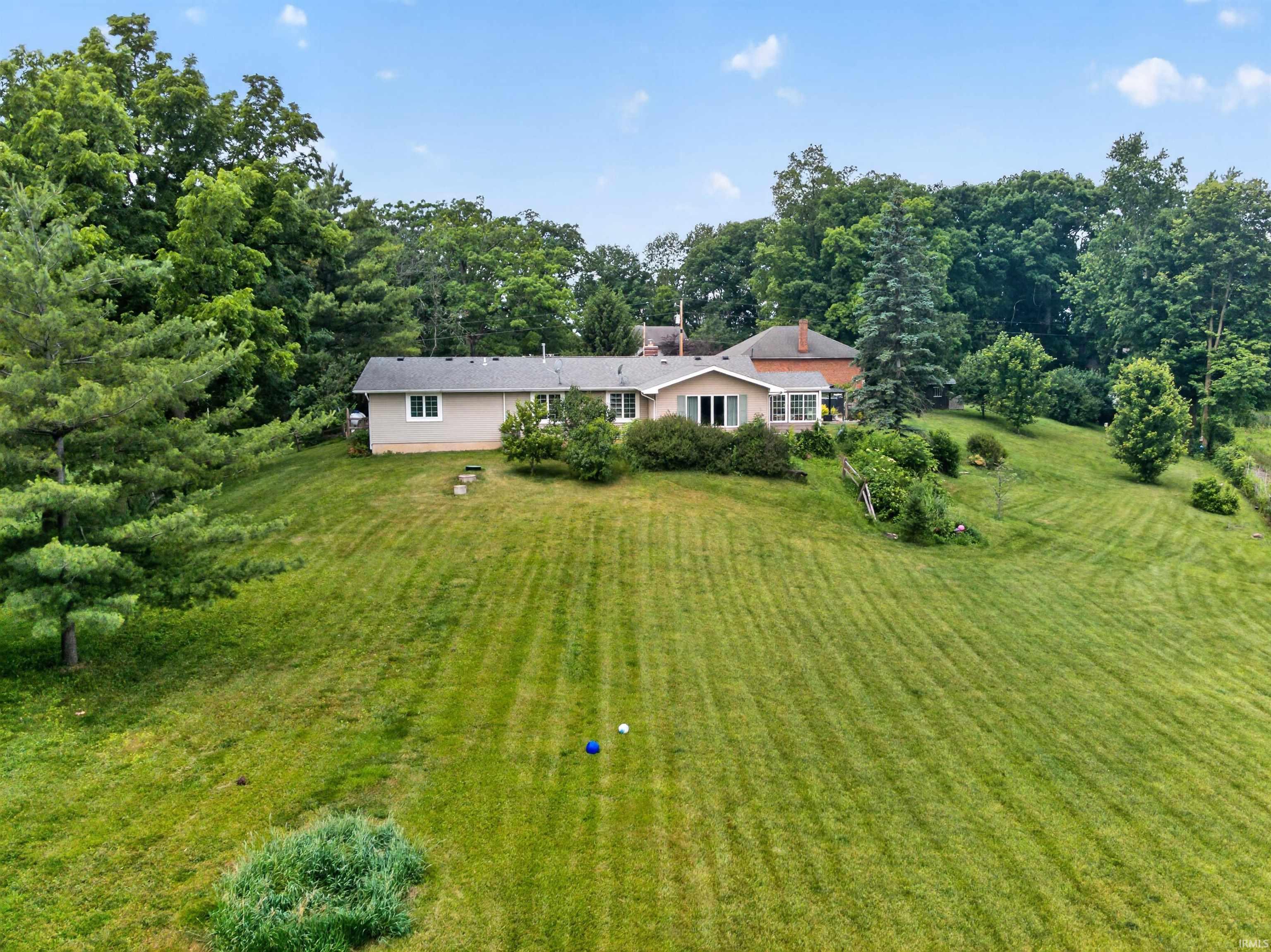 Expansive grassy hillside property with a ranch-style residence and a two-story brick structure