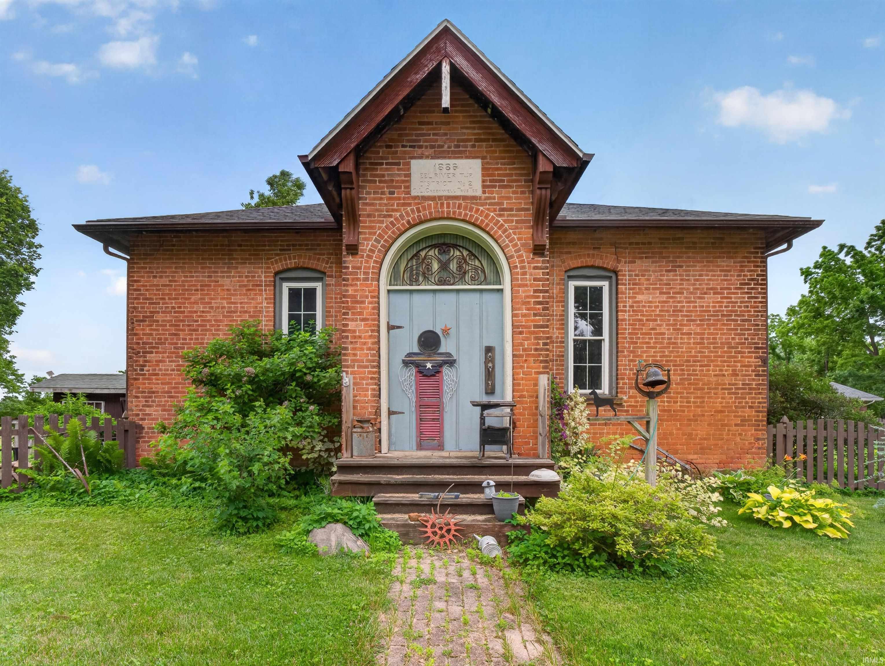 Brick exterior with an arched entry, prominent gable, and symmetrical windows