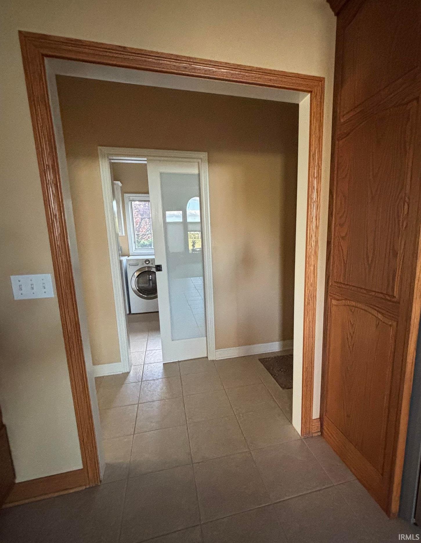 Archway entrance featuring wood-finish trim, tile flooring, and a sliding door with frosted glass