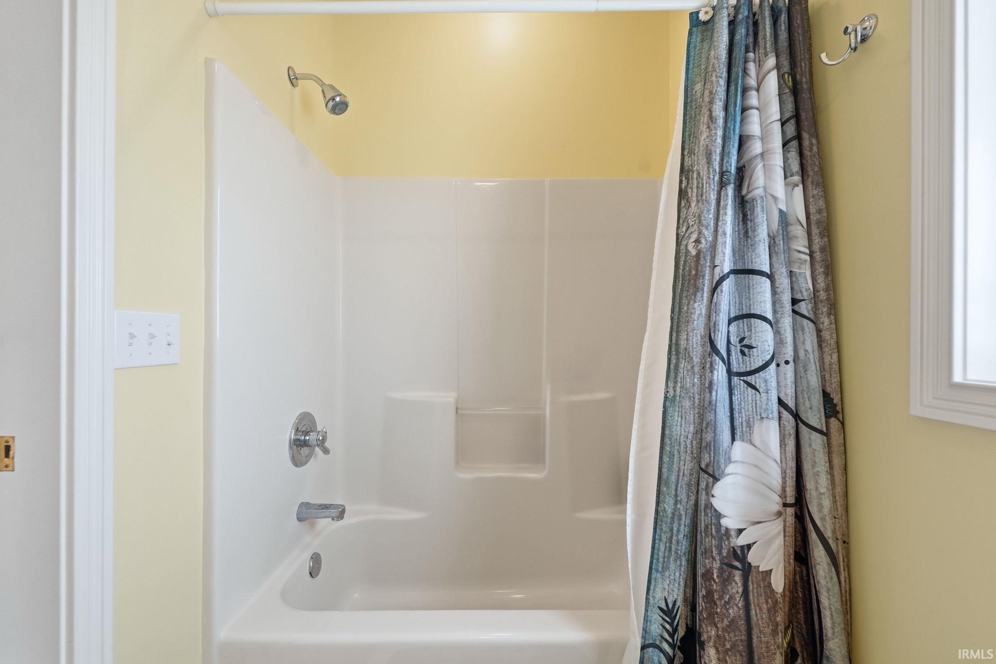 White acrylic shower and tub combination featuring an integrated shelf and chrome fixtures