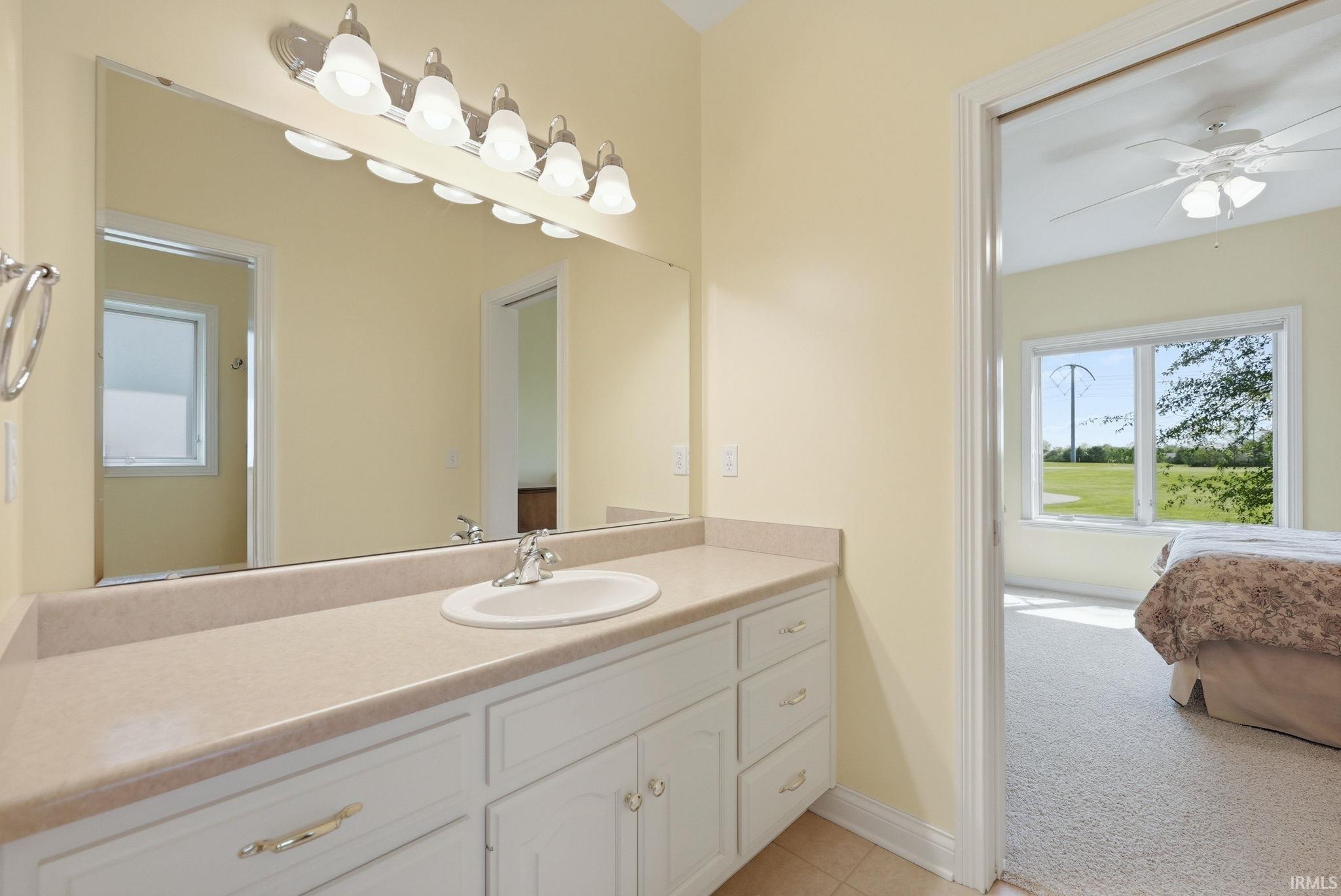 Bathroom vanity featuring a large wall-mounted mirror, white cabinetry with chrome hardware, and an integrated sink with a chrome faucet