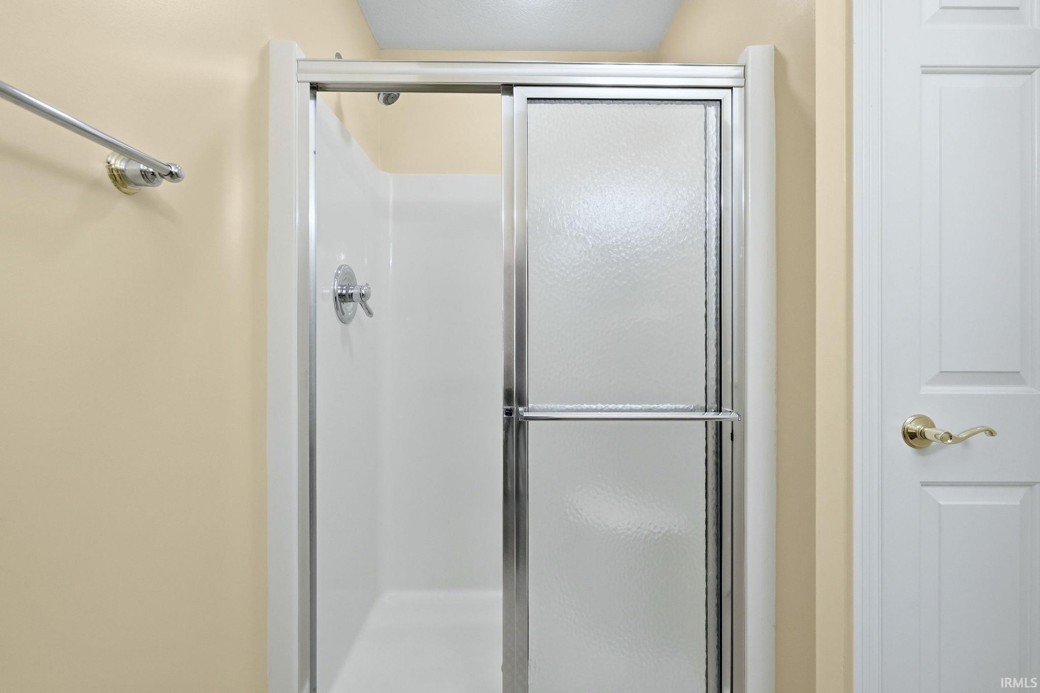 Shower enclosure with sliding frosted glass doors, chrome hardware, and a white fiberglass surround