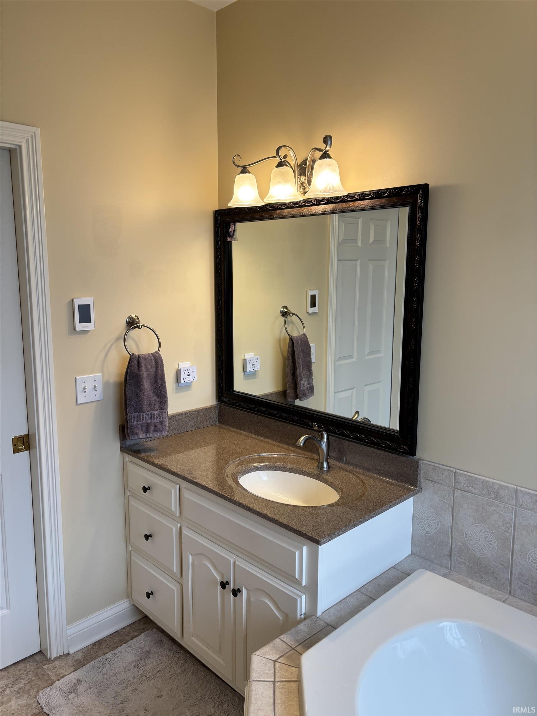 Bathroom vanity with a dark countertop and integrated oval sink, complemented by a three-light fixture