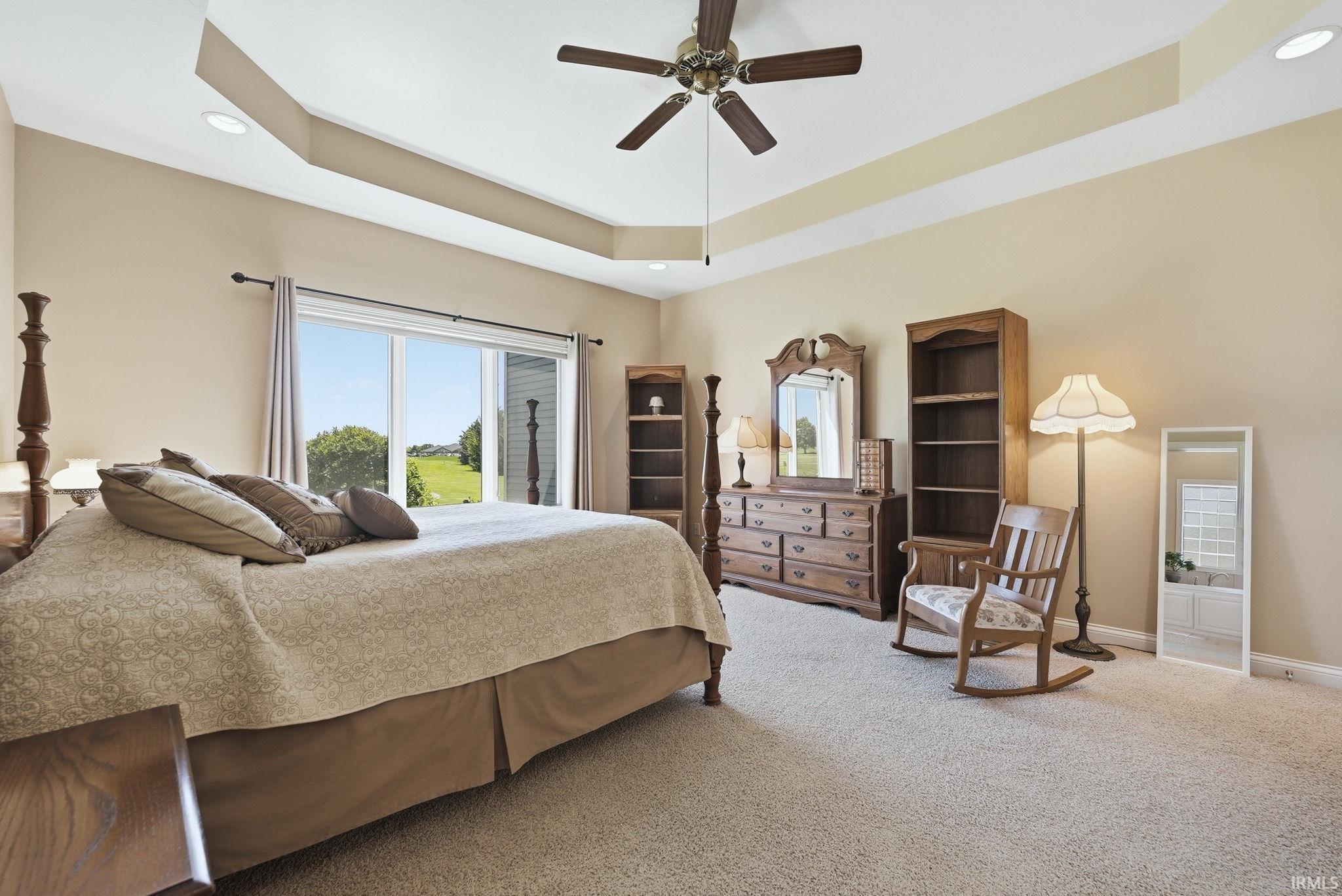 Recessed lighting illuminates the tray ceiling and ceiling fan