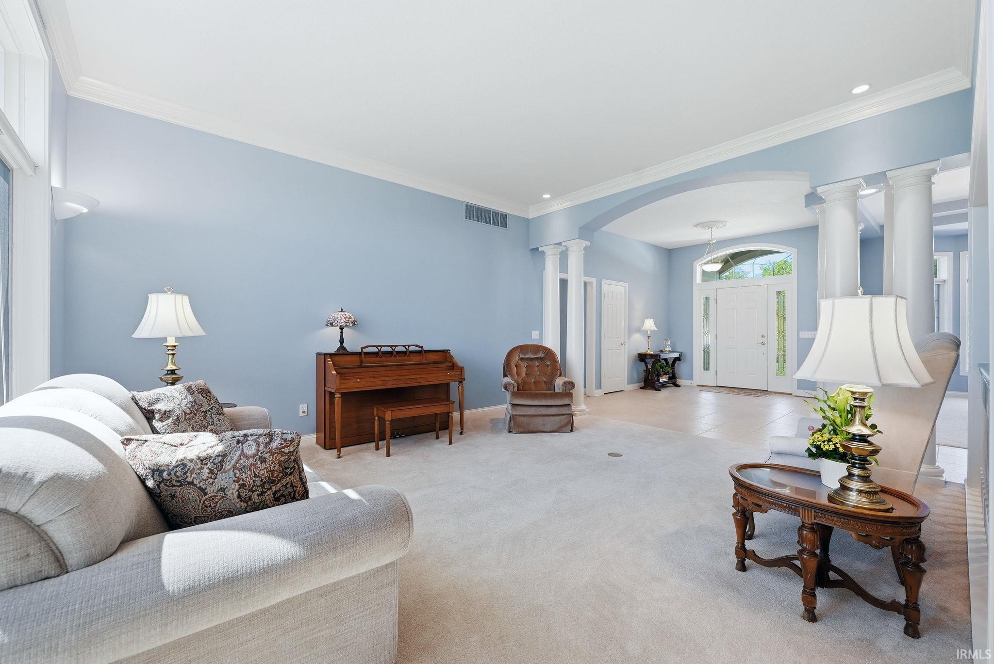 Carpeted living space featuring an arched entryway with decorative columns