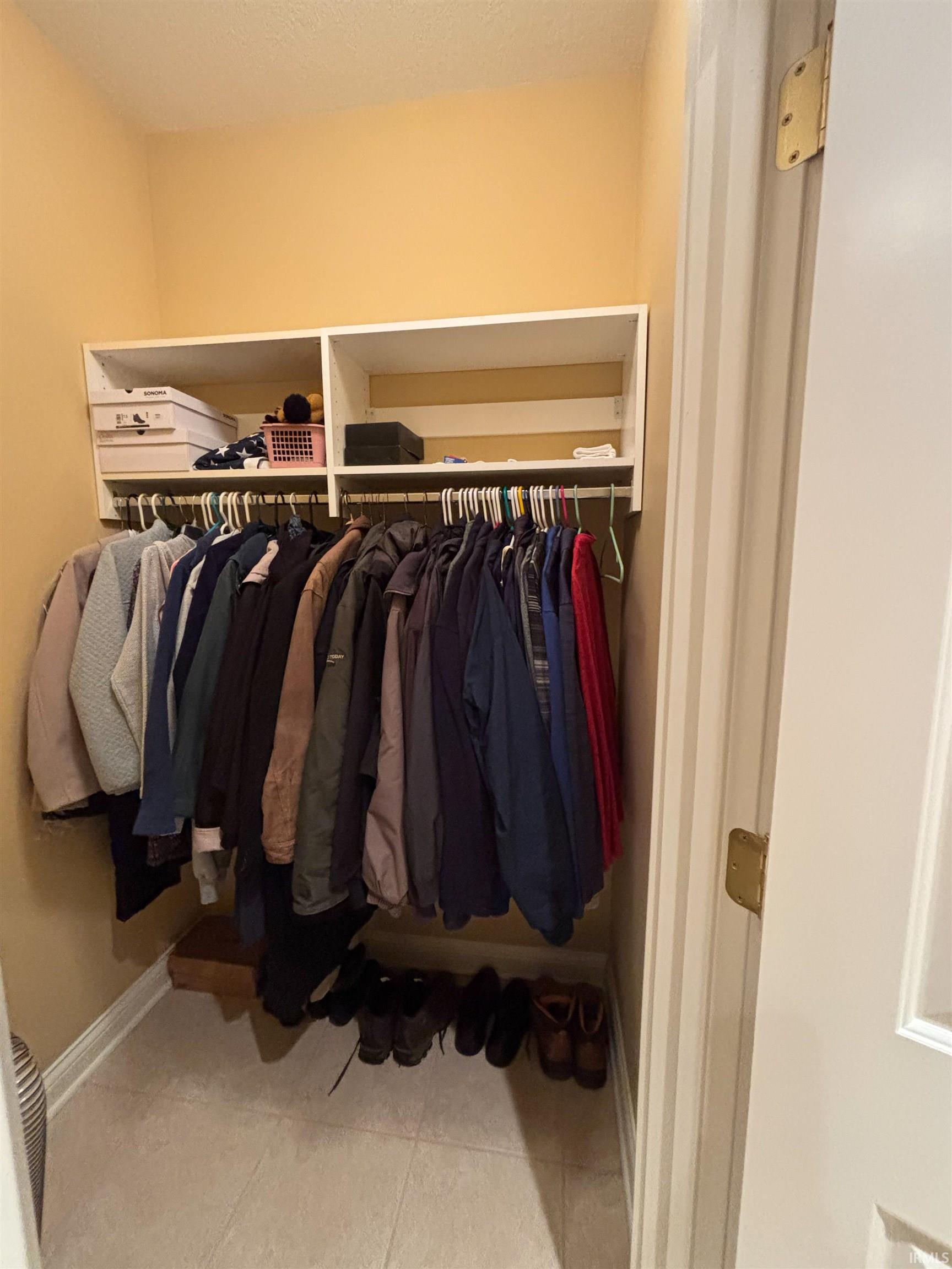 Integrated closet system featuring white shelving and a hanging rod, set against light yellow walls
