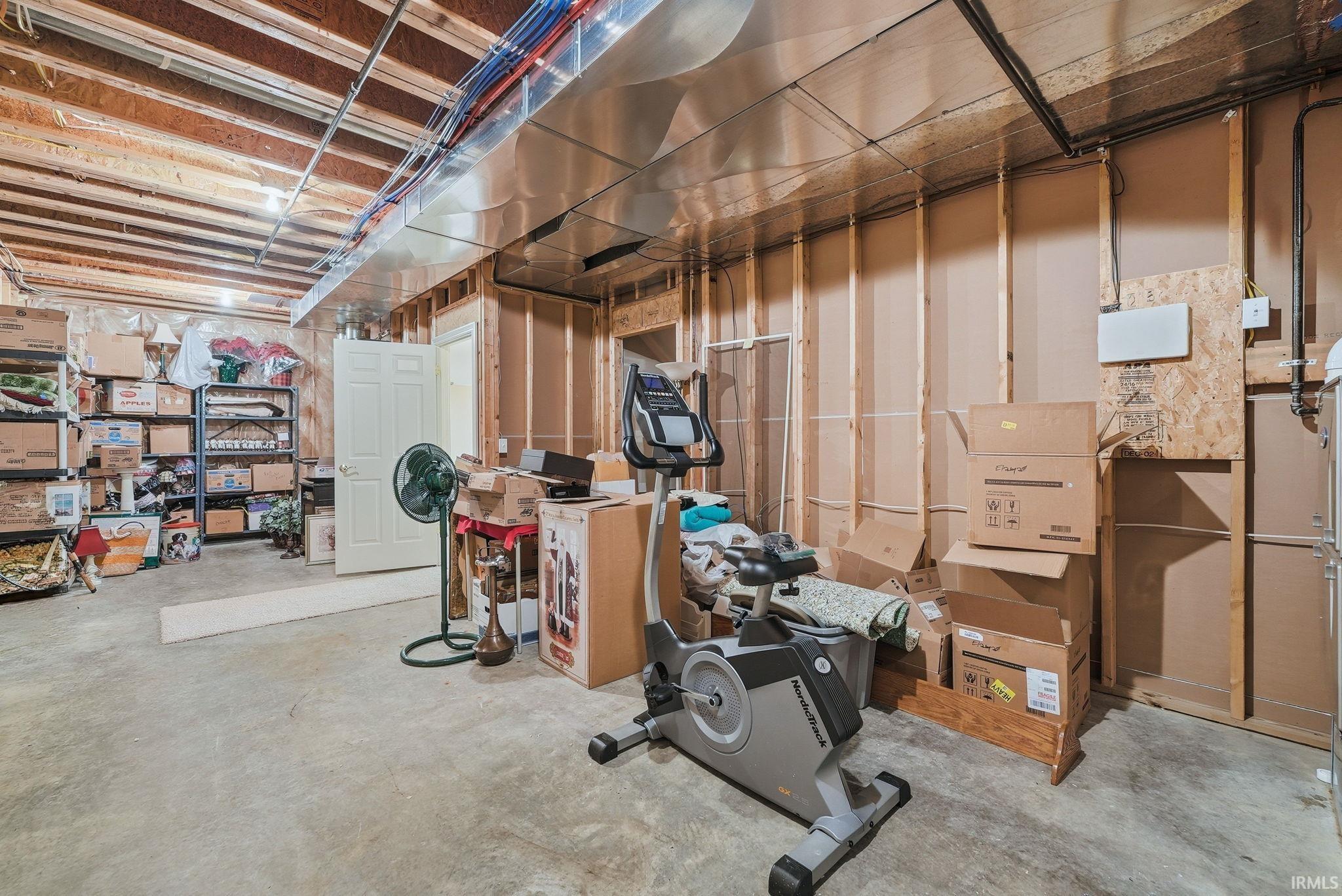 Unfinished basement space with exposed wood joists and concrete flooring