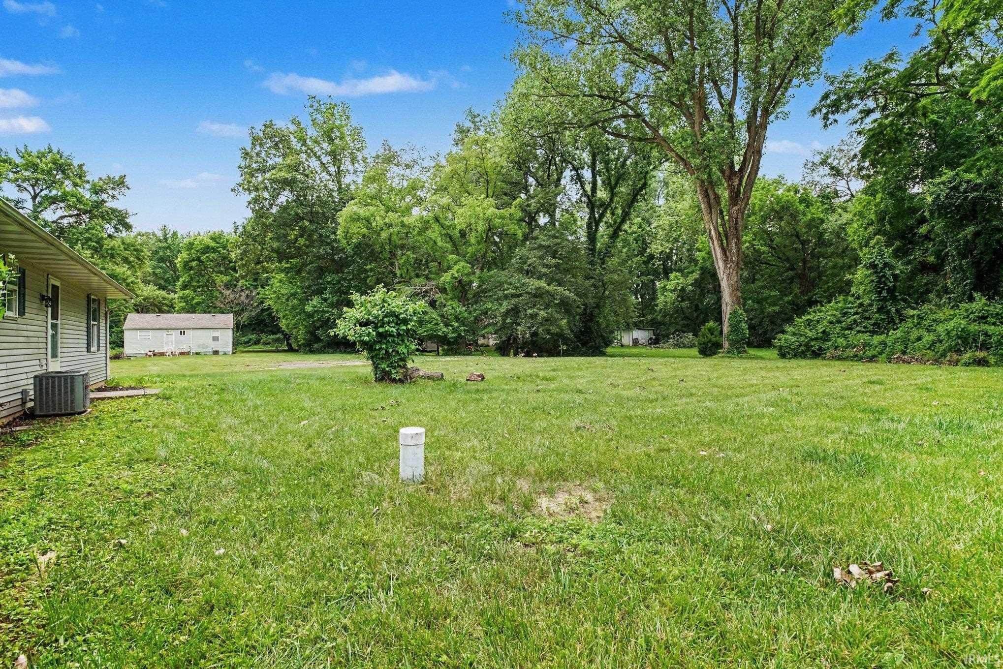 Expansive grassy yard with mature trees and a detached shed