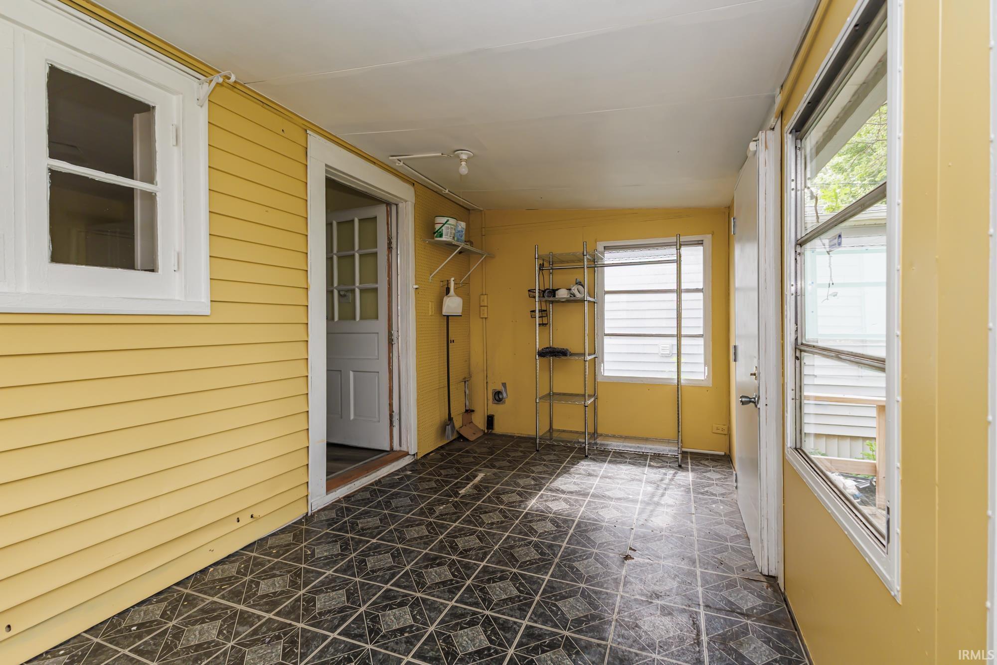 Enclosed porch featuring yellow siding walls and a patterned tile floor