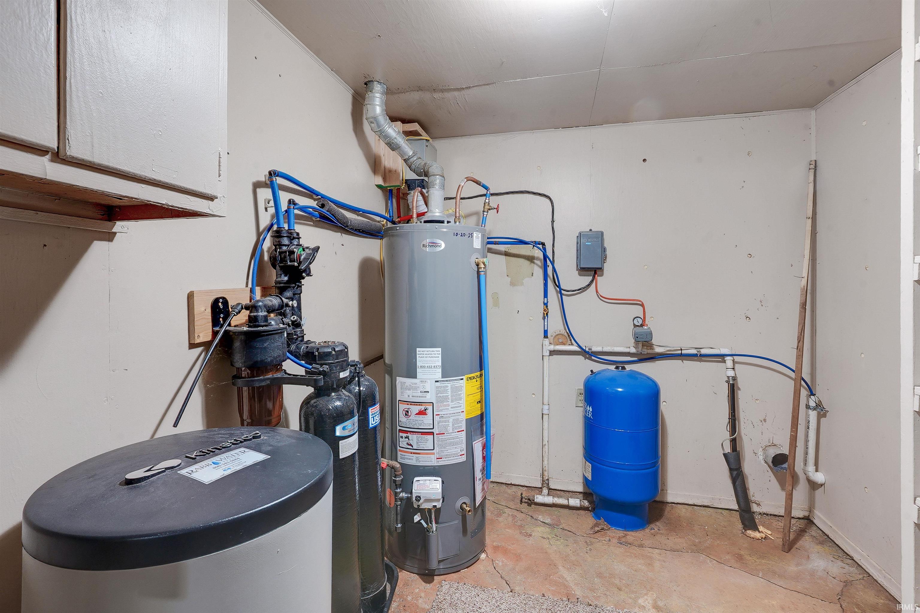 Utility area featuring a water heater, water softener system, and blue pressure tank