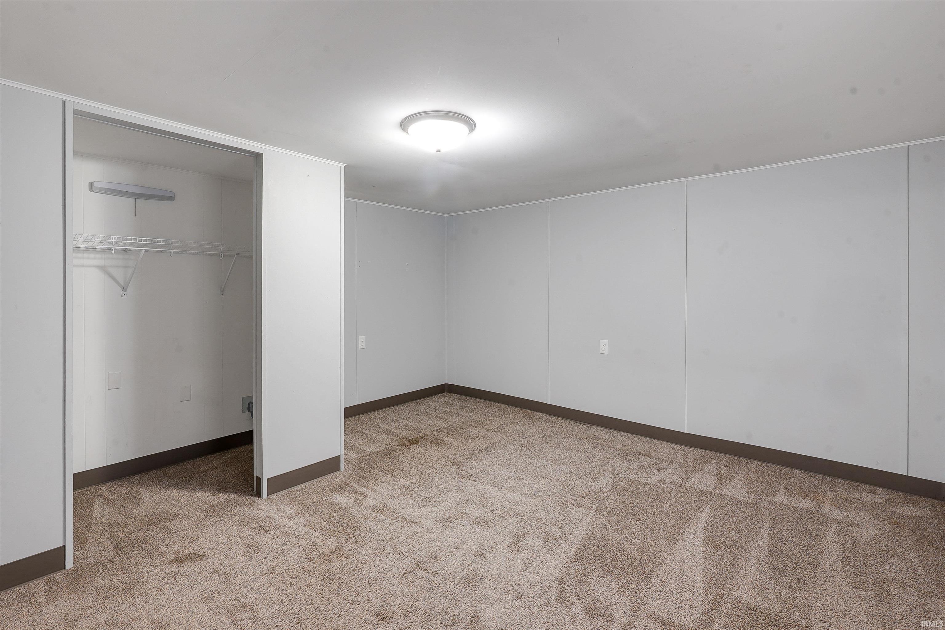 Carpeted room with light grey panel walls and contrasting dark baseboards