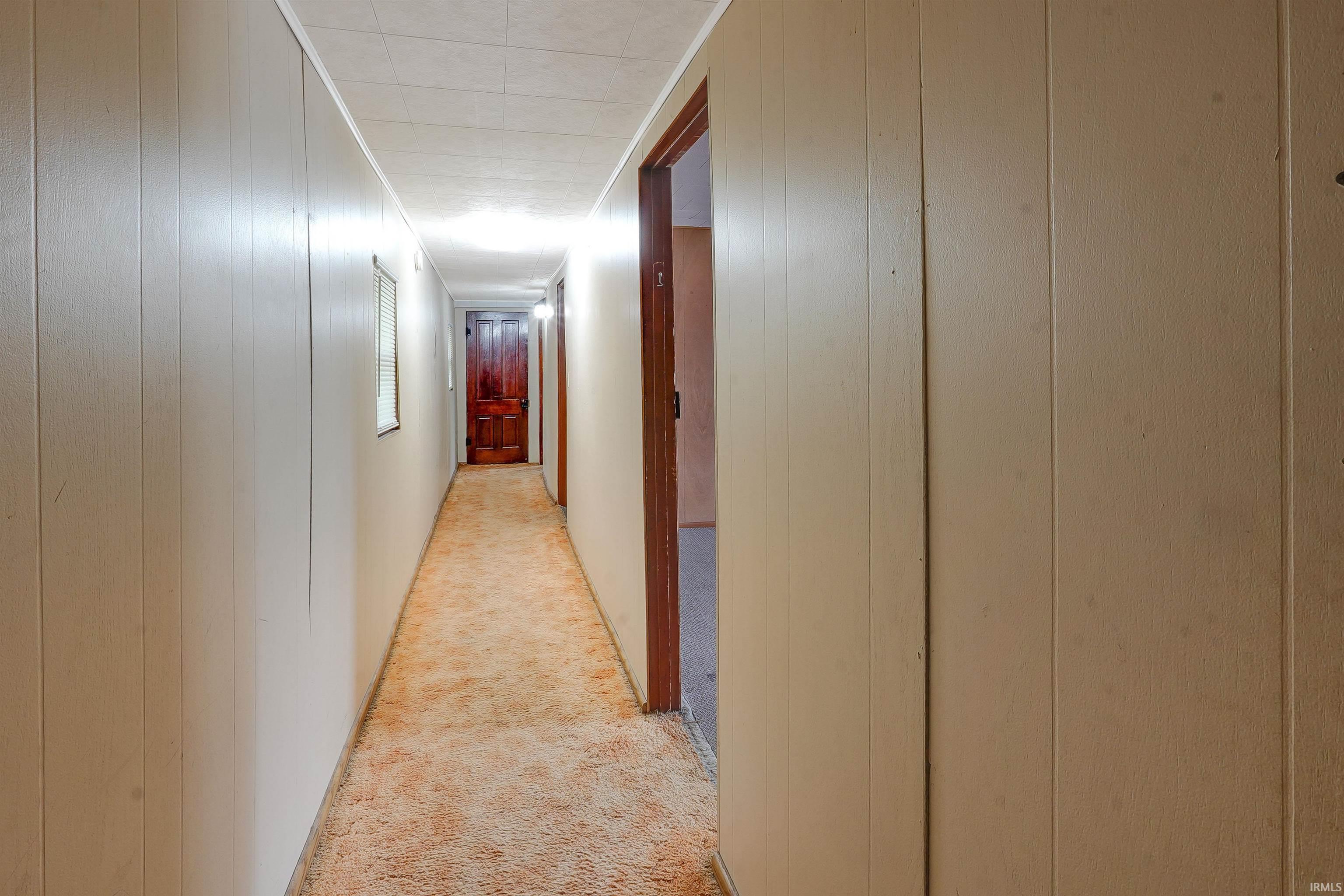 Hallway featuring light-colored vertical paneling, textured ceiling, recessed lighting, and a neutral carpet runner