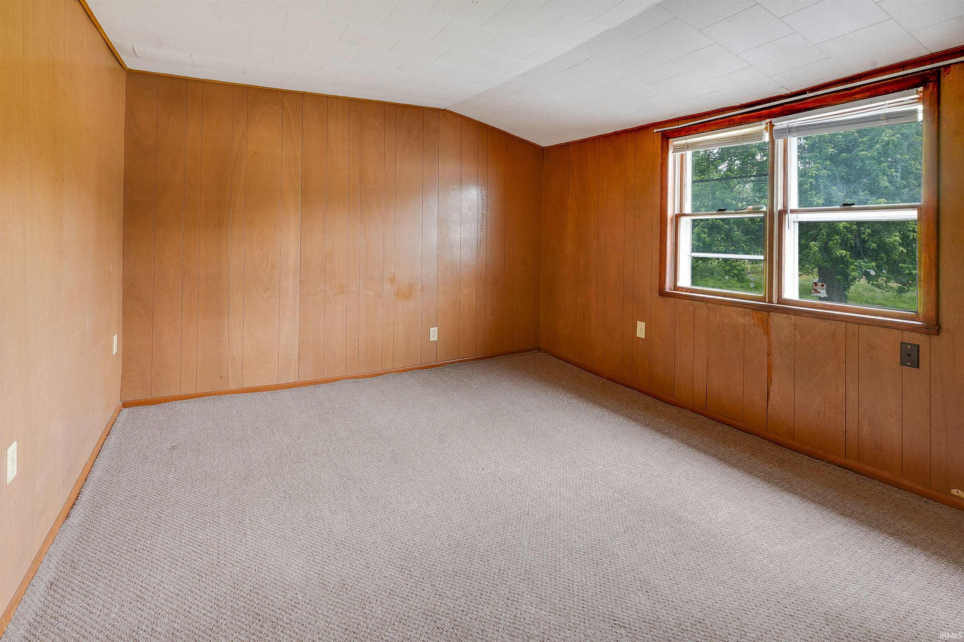 Room featuring wood paneling, a textured ceiling, gray carpeting, a large window, and multiple electrical outlets