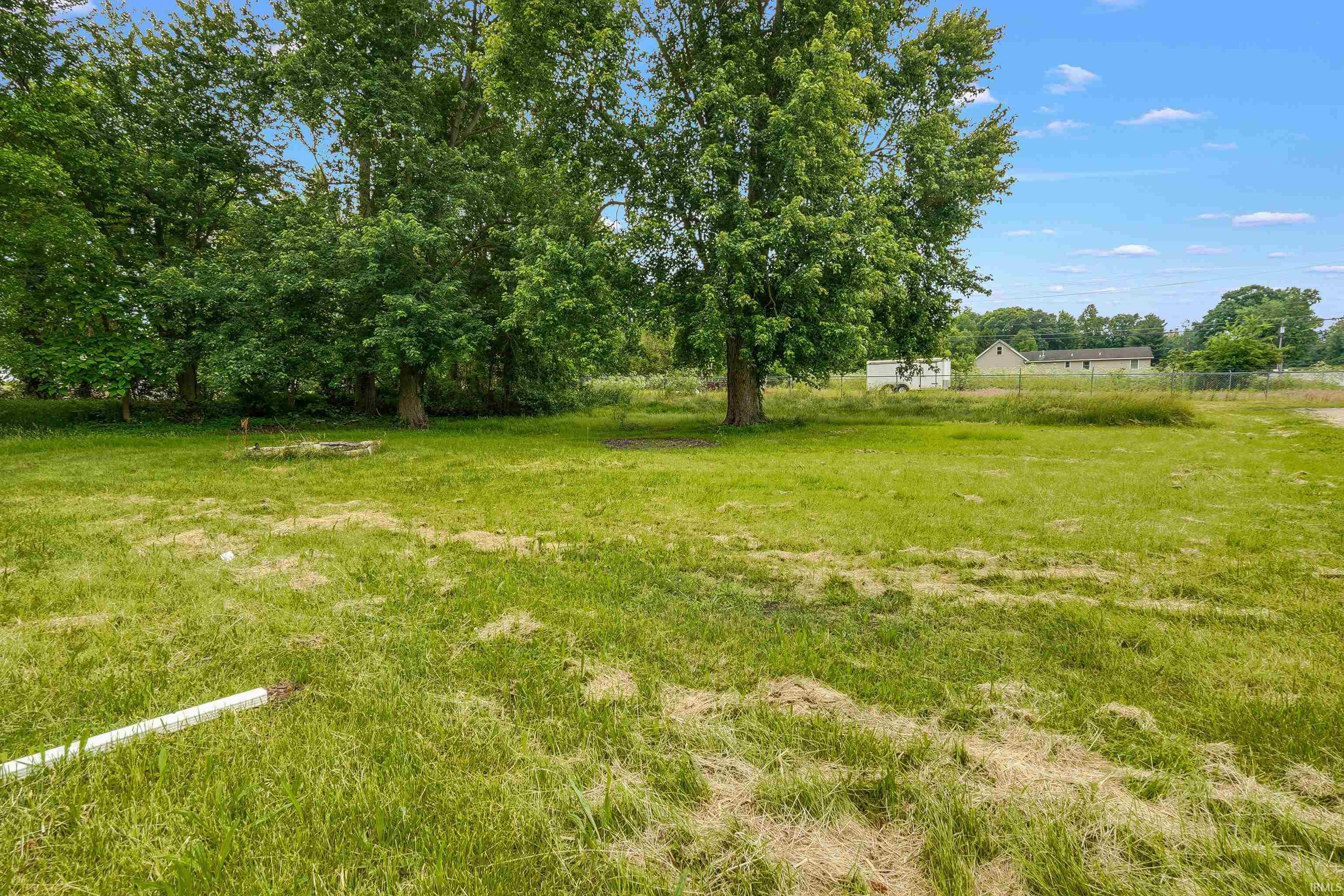 Expansive green lot featuring mature trees