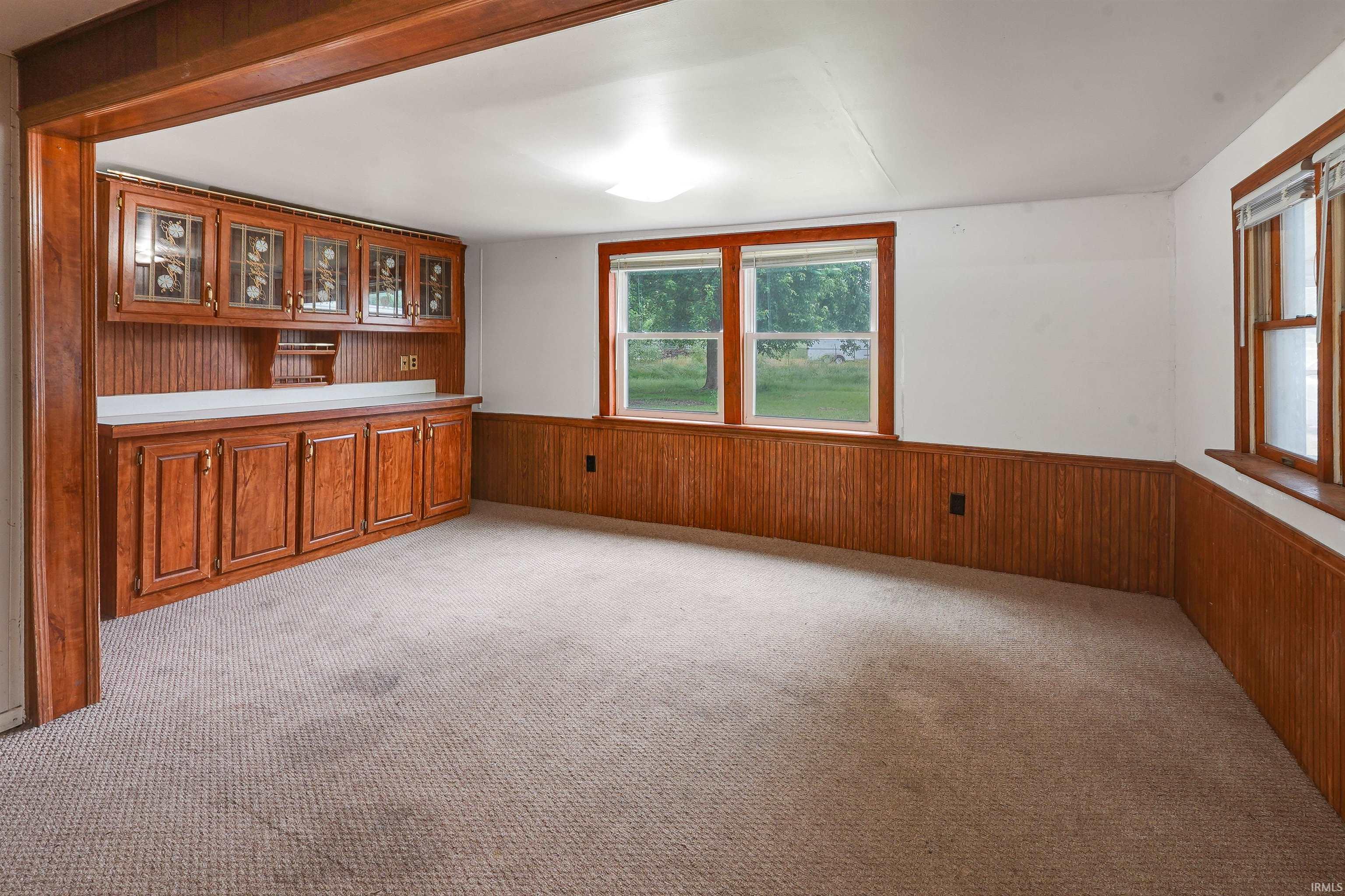 Built-in wood cabinetry with glass-front upper doors, a white countertop, and beadboard paneling