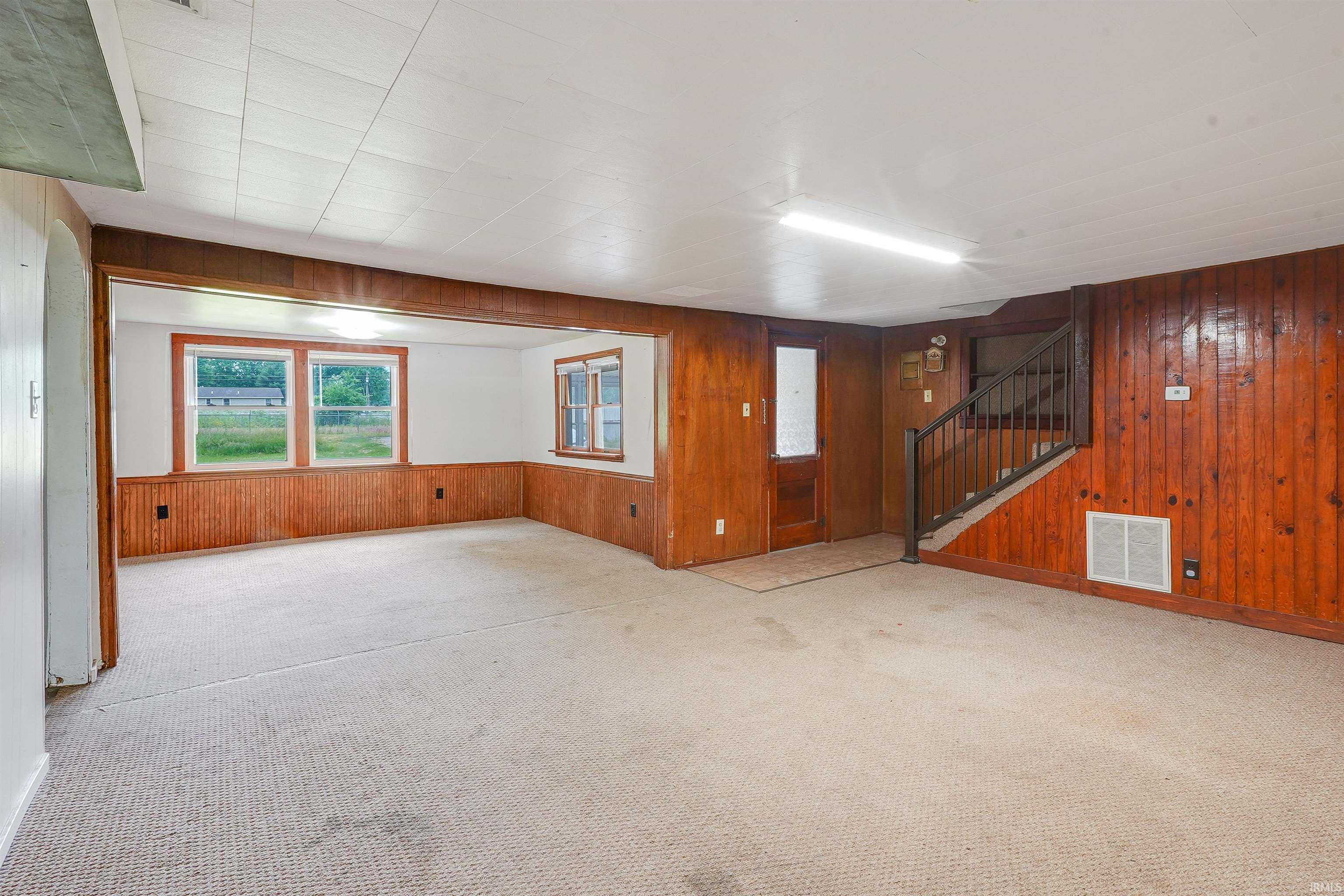 Spacious interior featuring wood paneling, white walls, and light-colored carpet