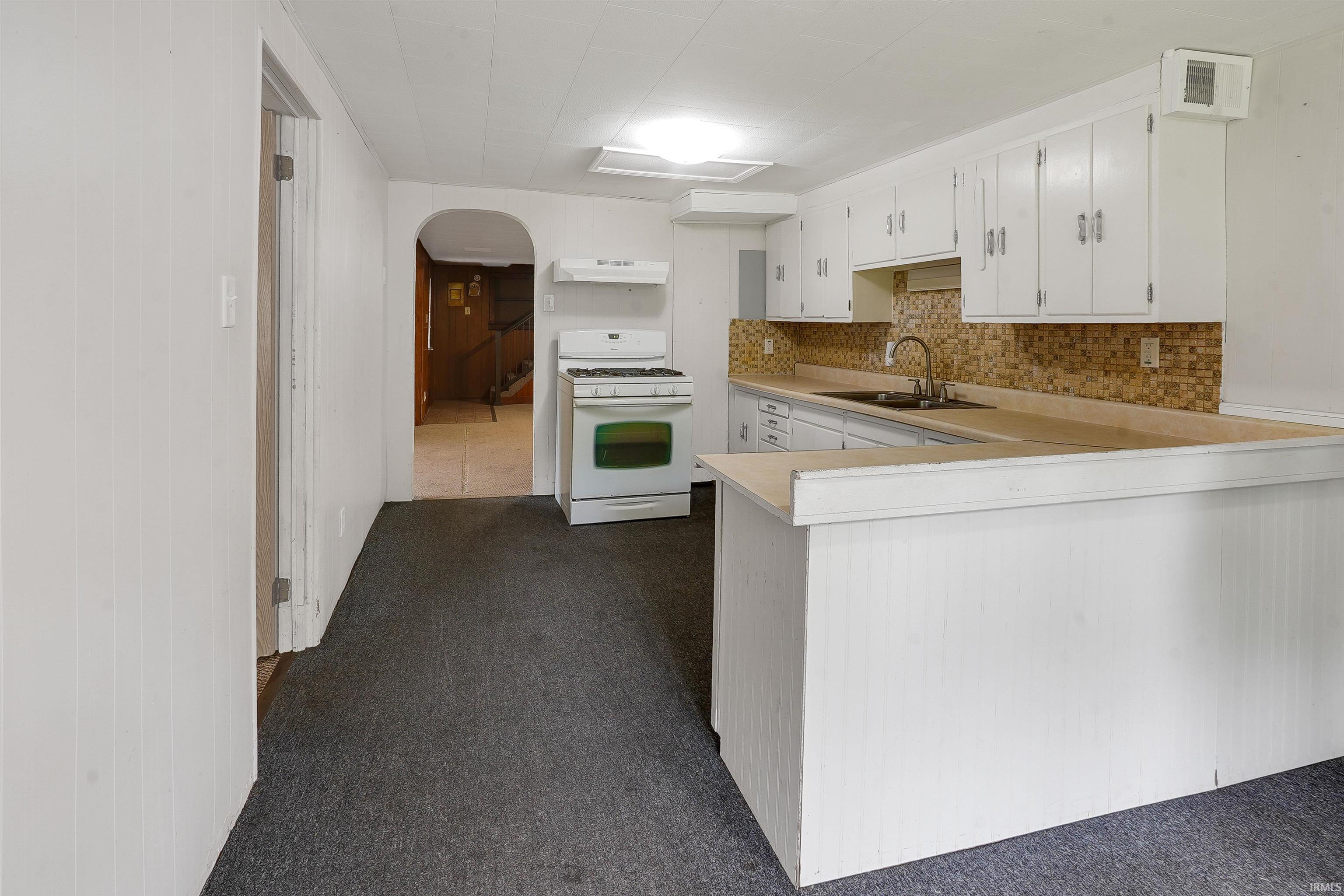 Kitchen with white cabinetry, a U-shaped countertop, and a tiled backsplash