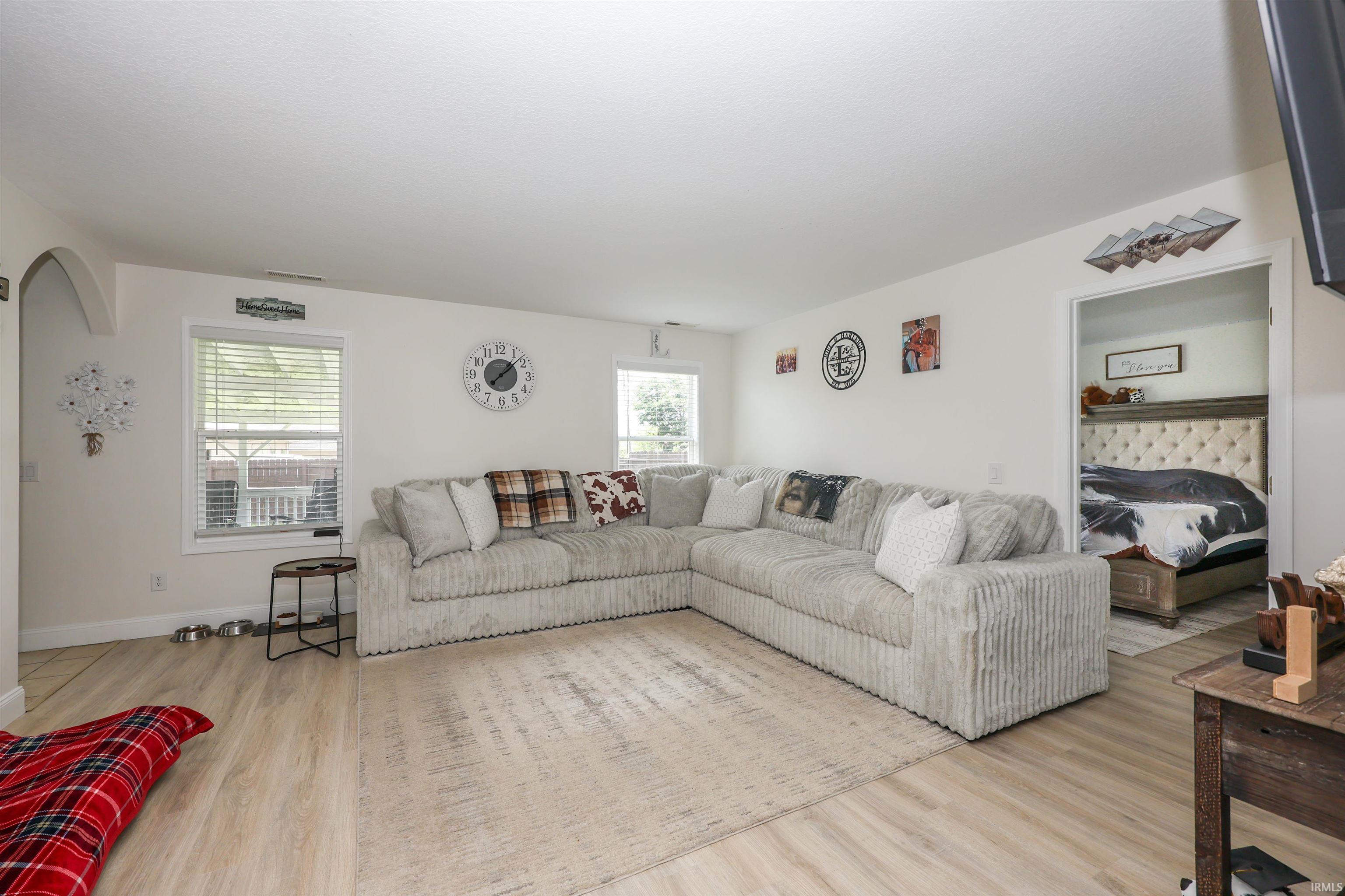 Spacious living area featuring light wood-finish flooring, white baseboards, and neutral wall paint
