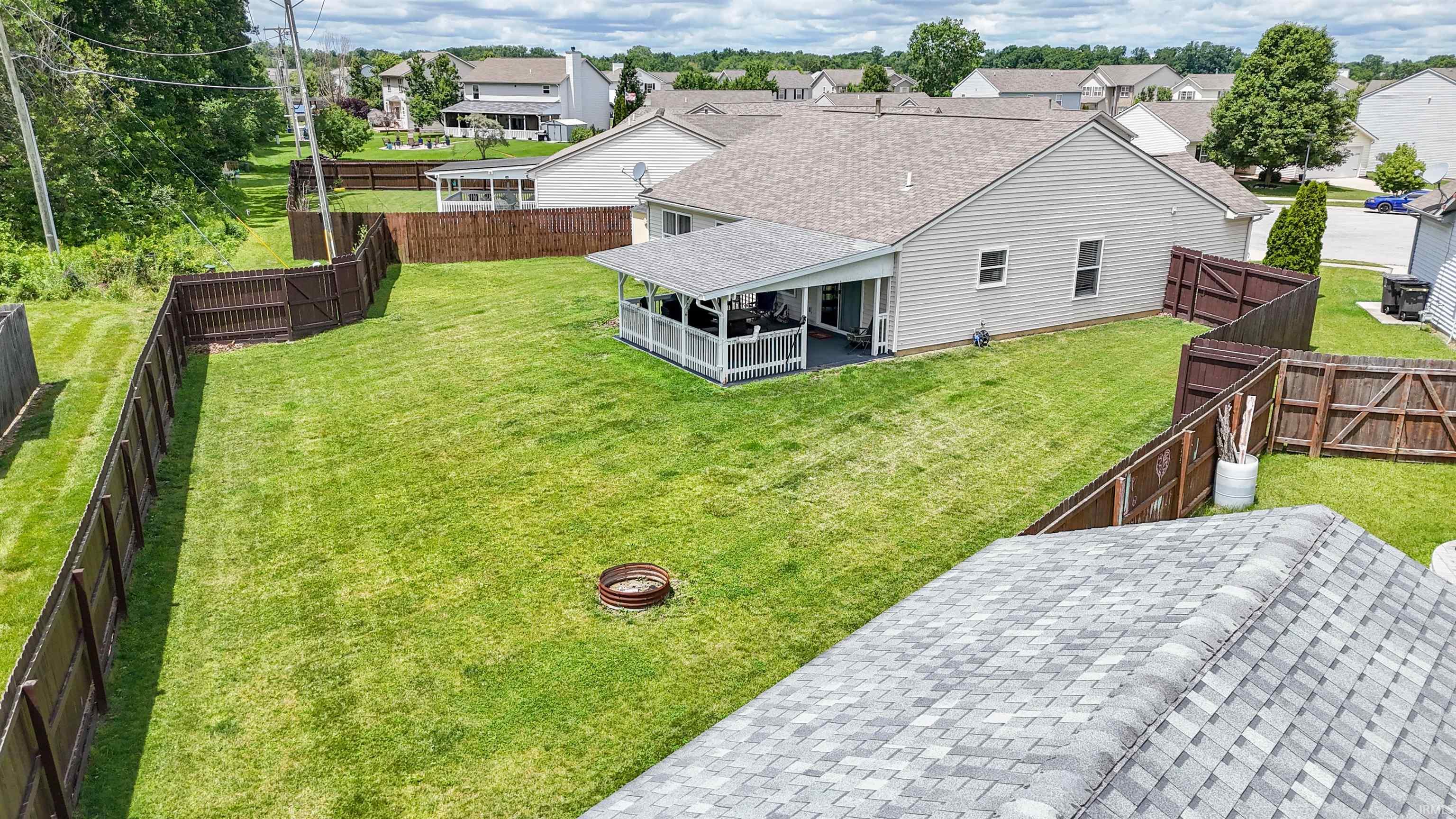 Expansive backyard featuring a manicured lawn, full perimeter privacy fencing, and a fire pit