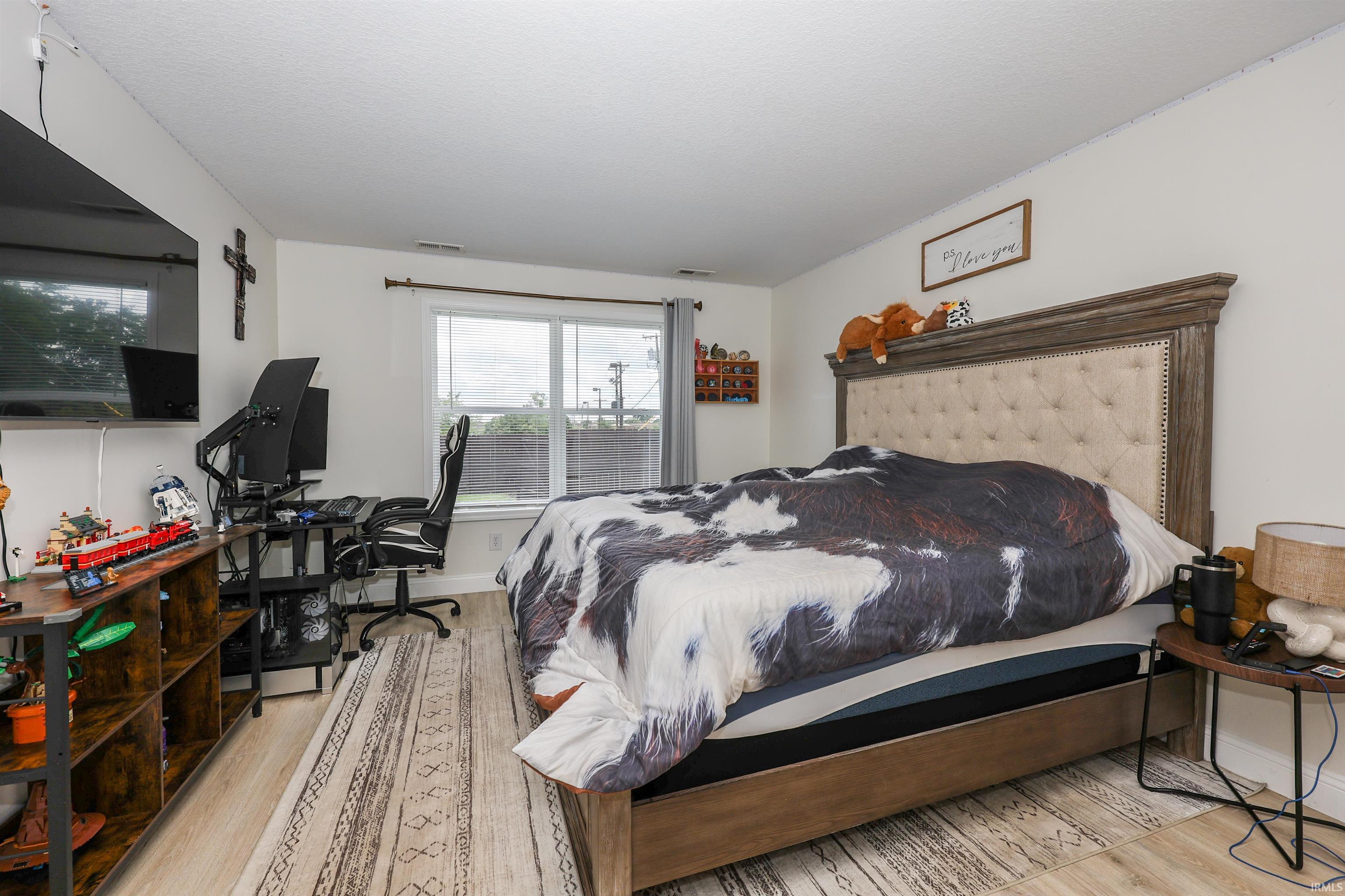 Spacious bedroom featuring wood-finish flooring and a large window