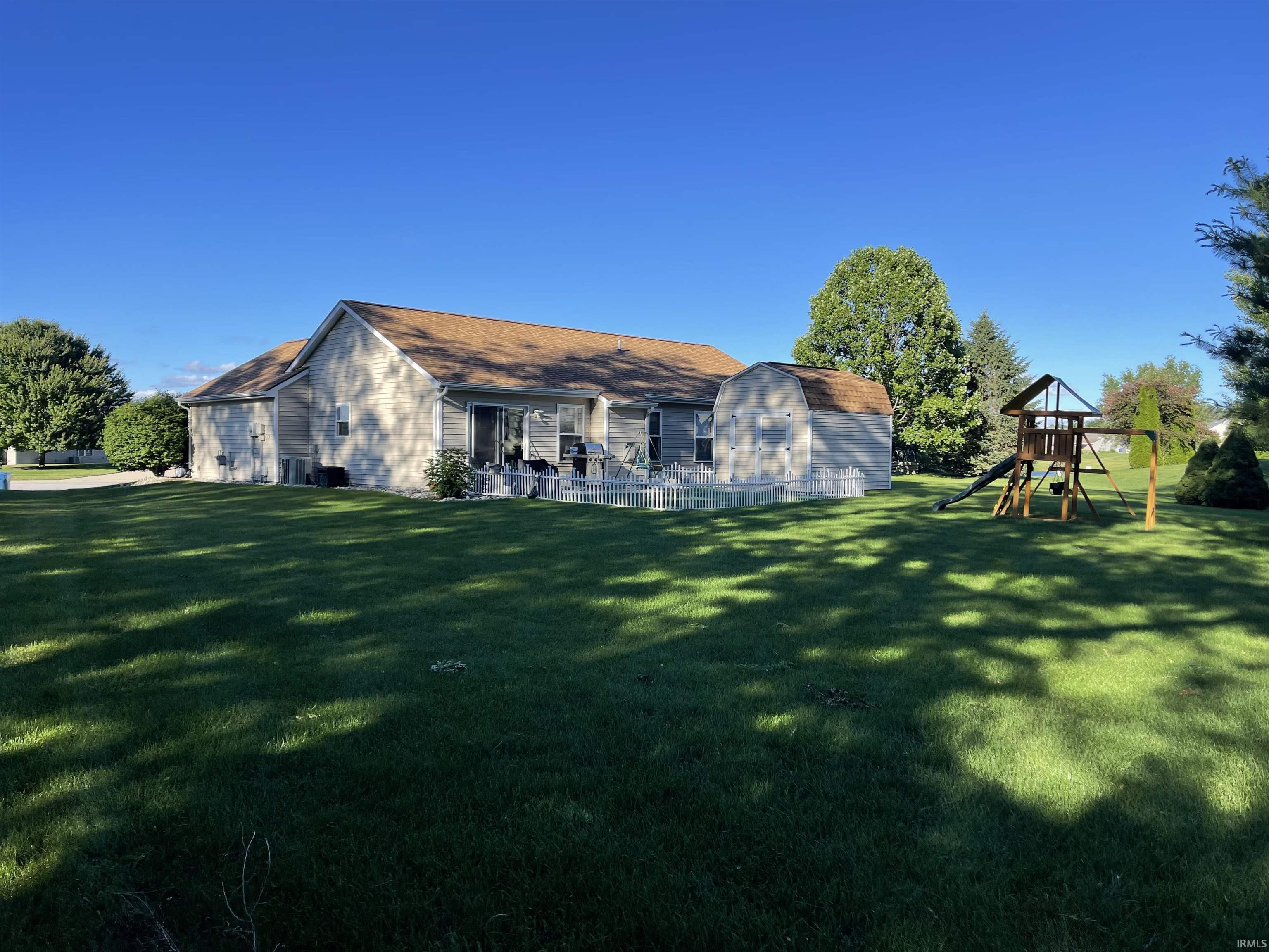 Expansive grassy lawn with mature trees and a detached shed