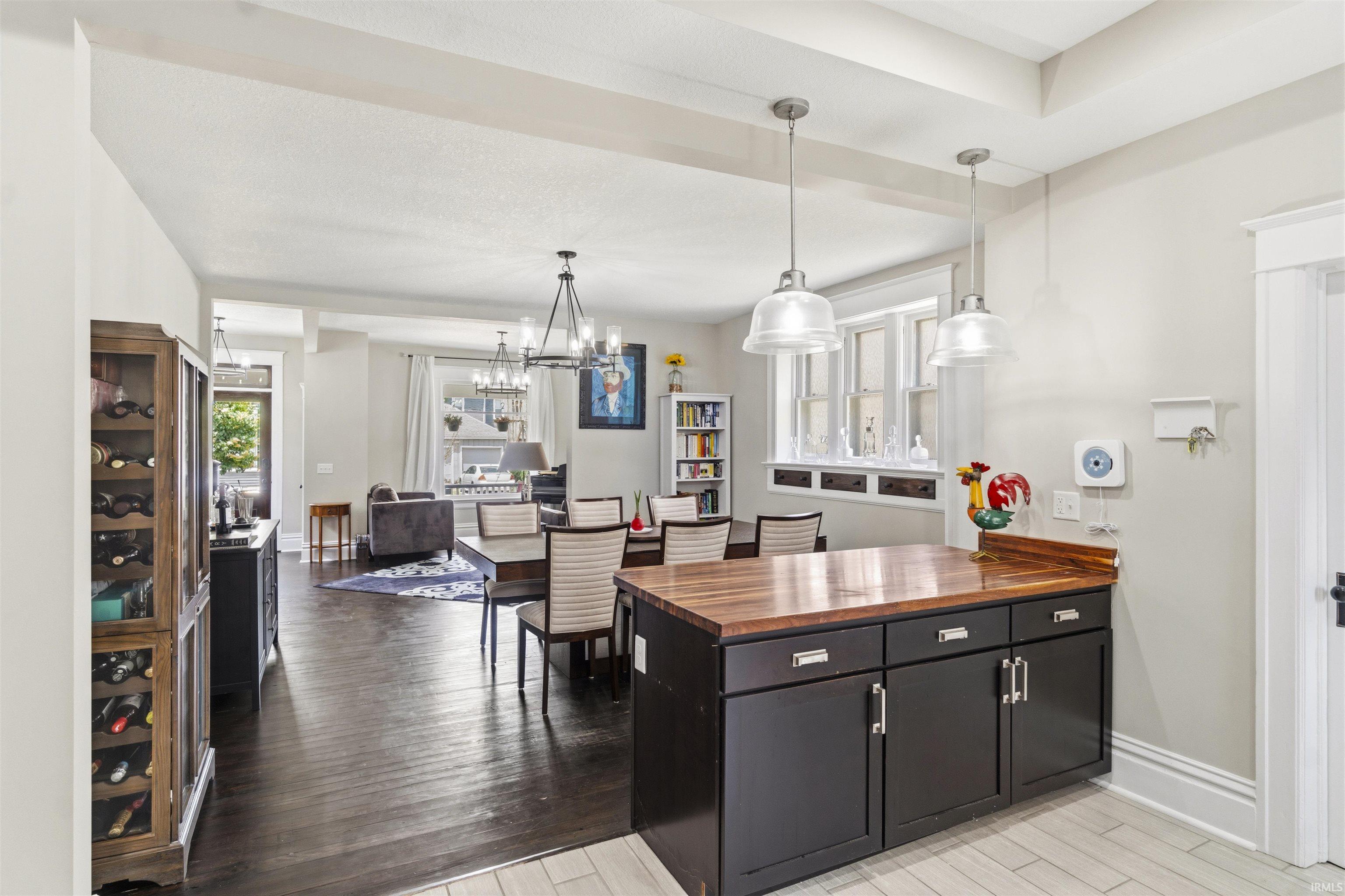 Kitchen island with a butcher block countertop, dark cabinetry, and brushed nickel hardware