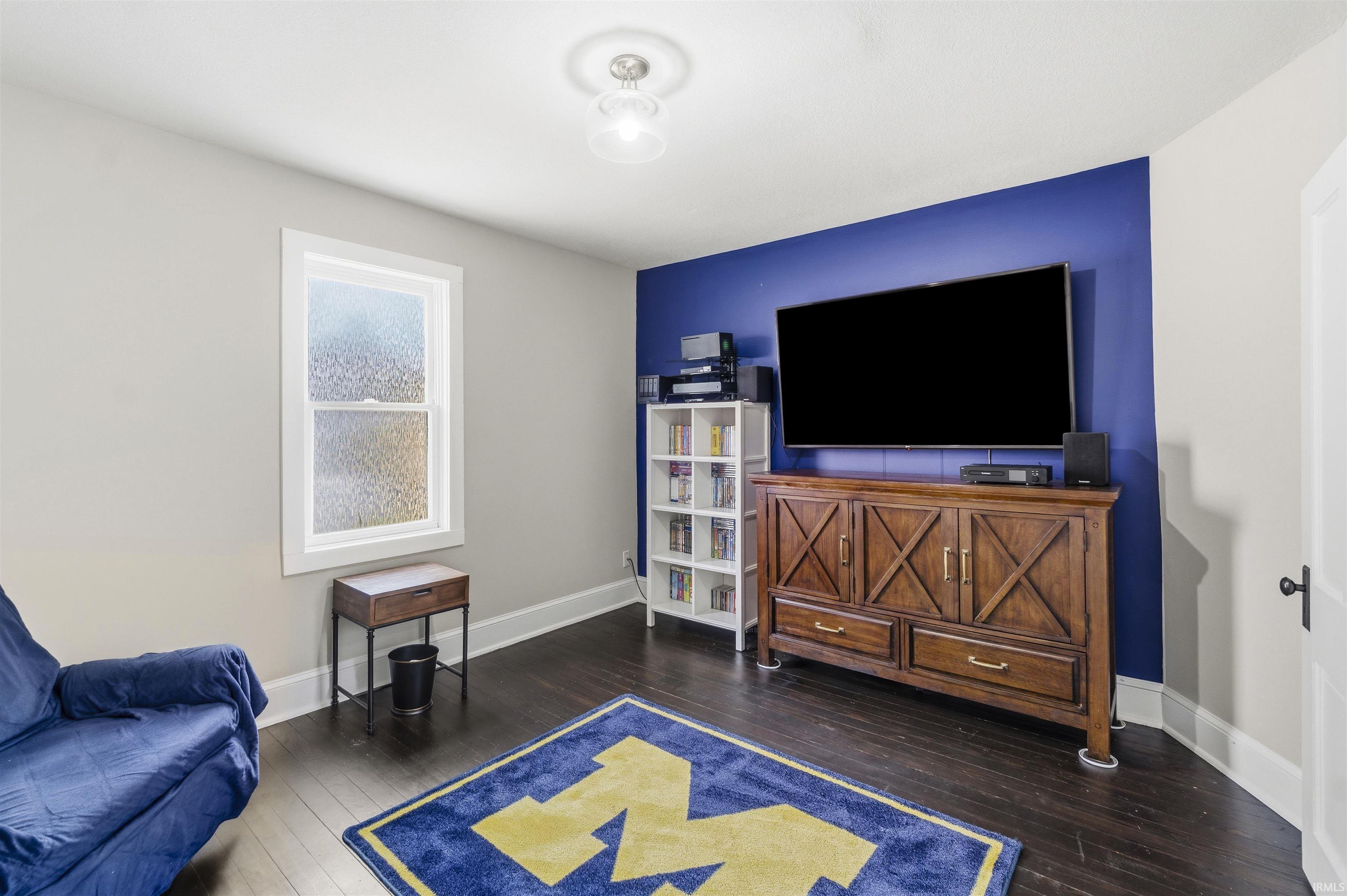 Hardwood-finish flooring features throughout this room with a contrasting accent wall