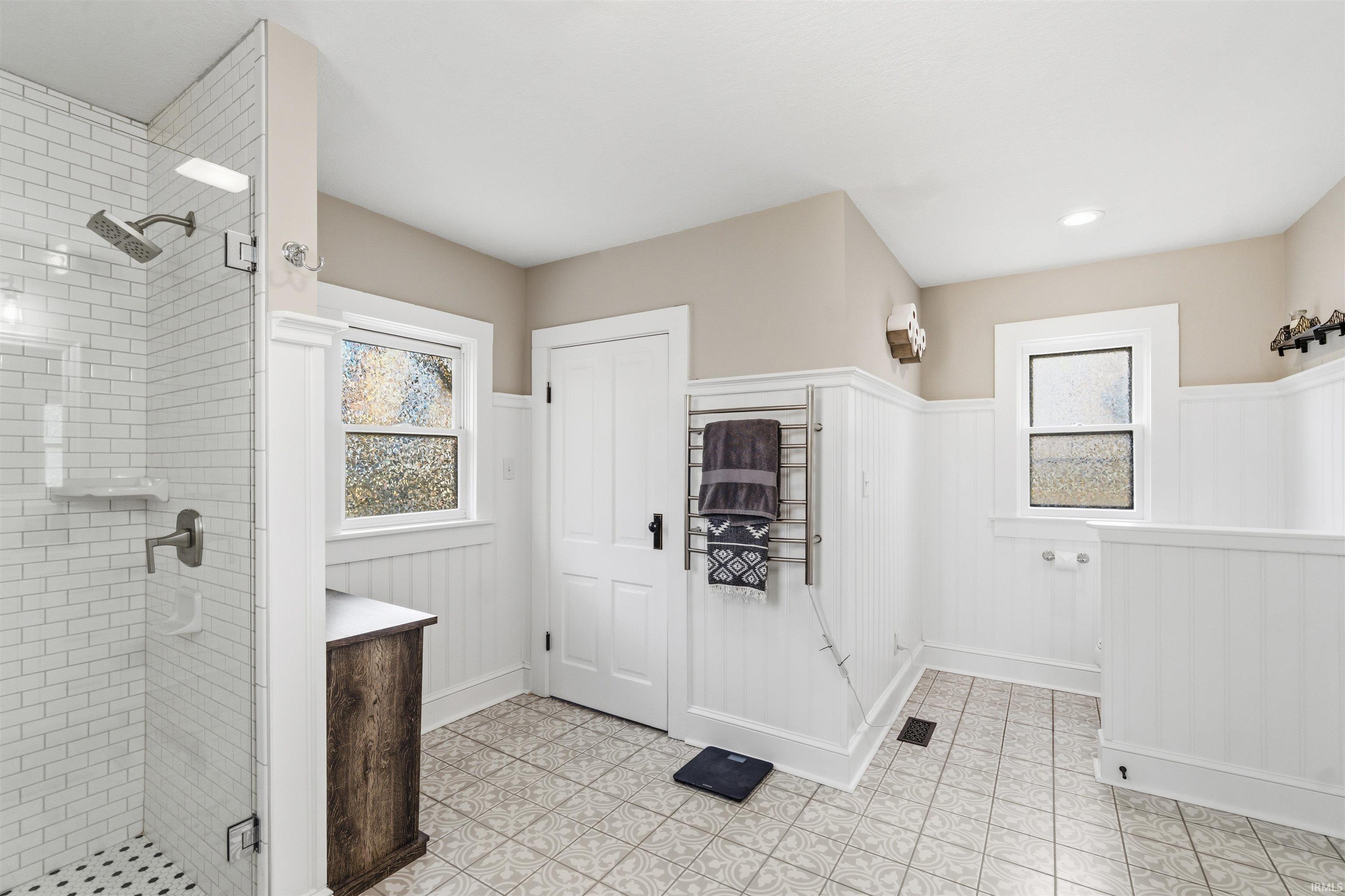 Contemporary bathroom featuring a glass-enclosed shower with subway tile, mosaic tile flooring, and a rainfall showerhead