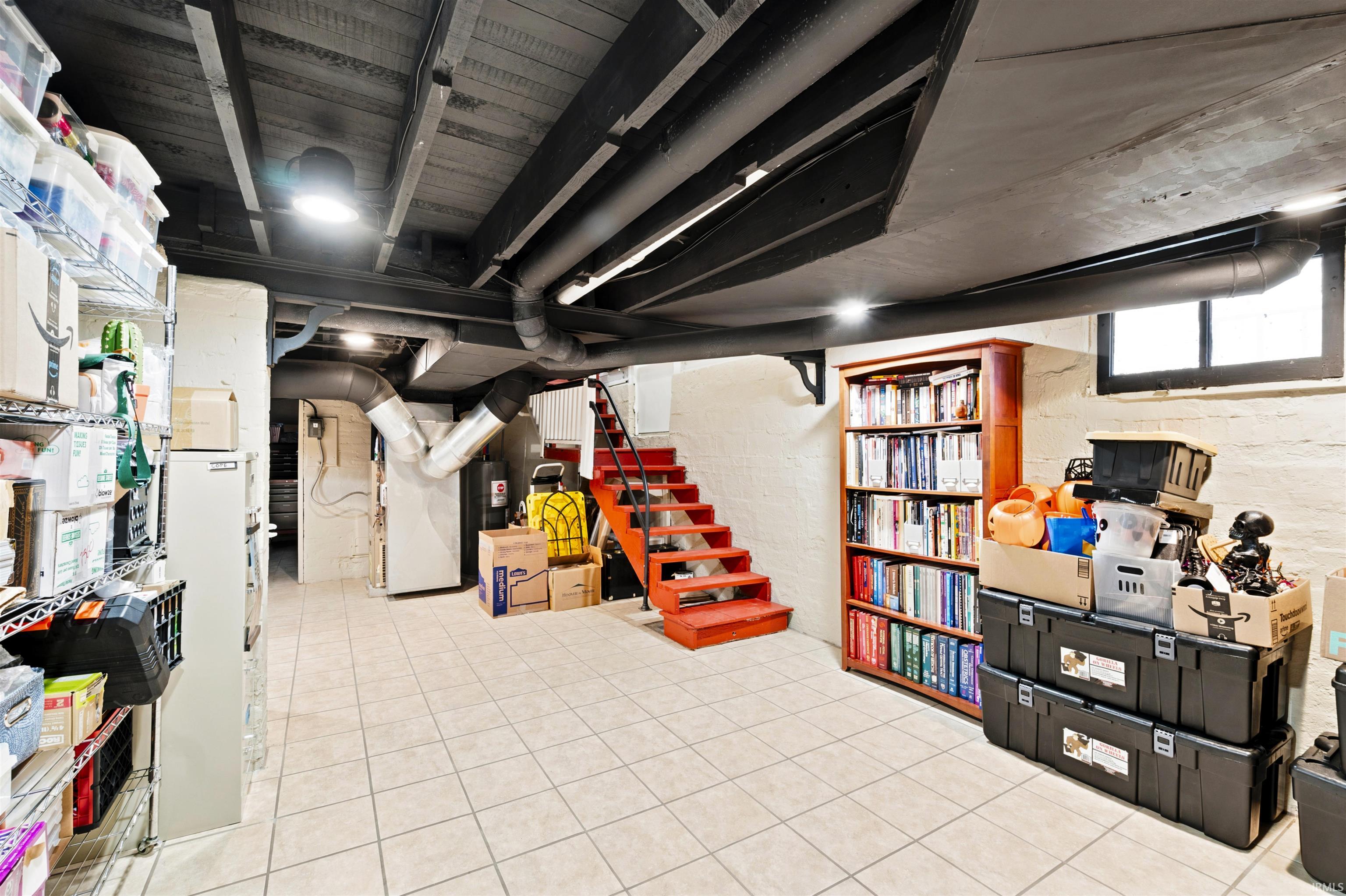 Finished basement area featuring tile flooring, painted ceiling joists, and exposed ductwork