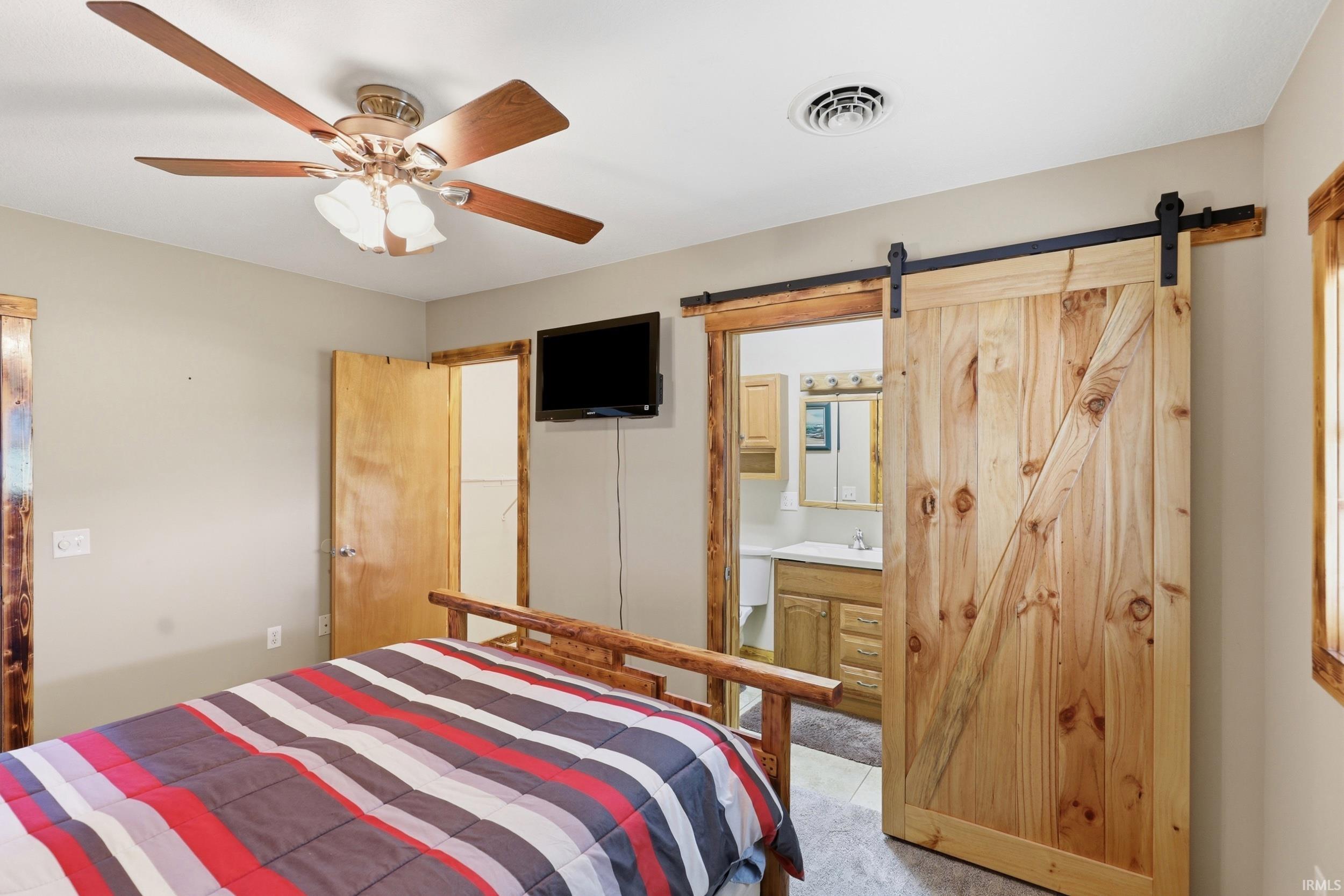 Interior room featuring a natural wood barn door, wood-finish ceiling fan, and light-toned walls
