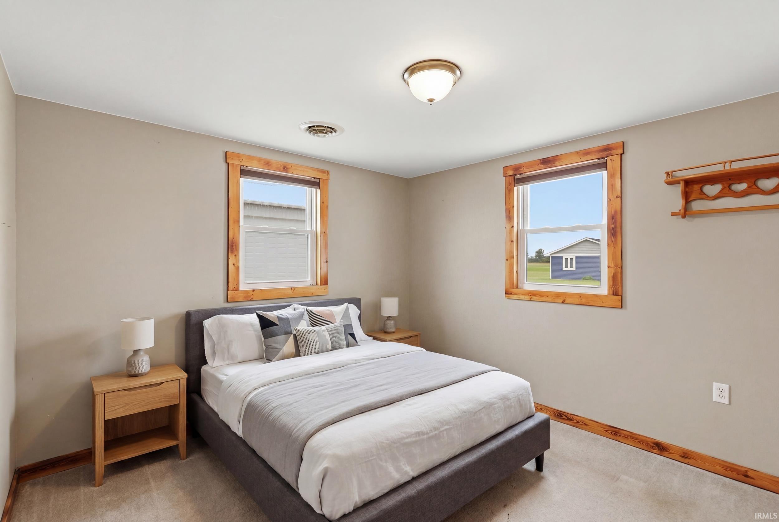 Bedroom featuring two windows with natural wood trim and a flush-mount ceiling light fixture